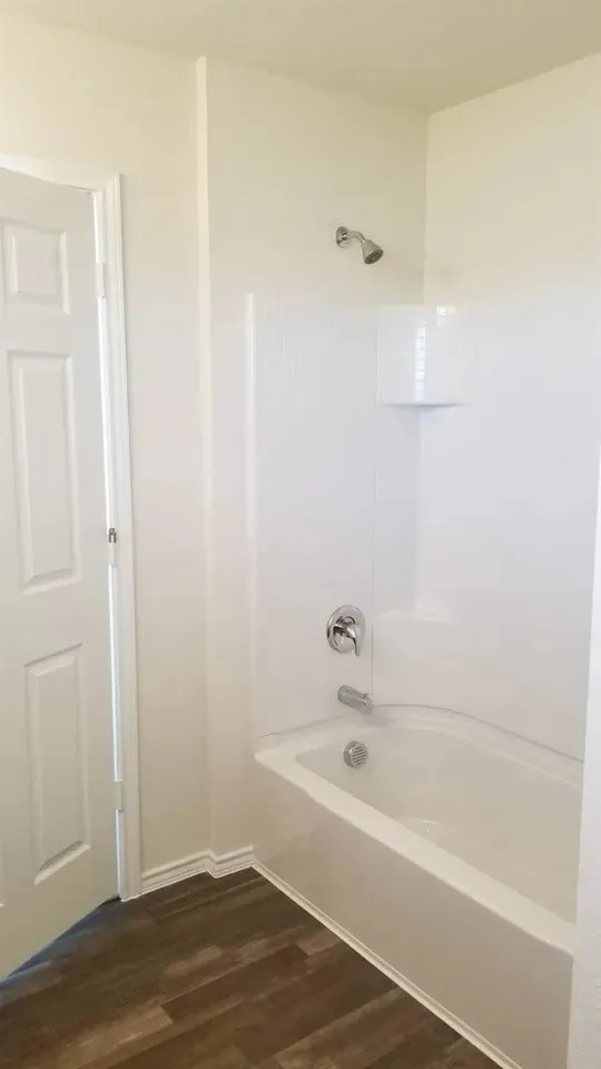 Master Bath with White shower/tub combination with chrome fixtures and integrated shelving