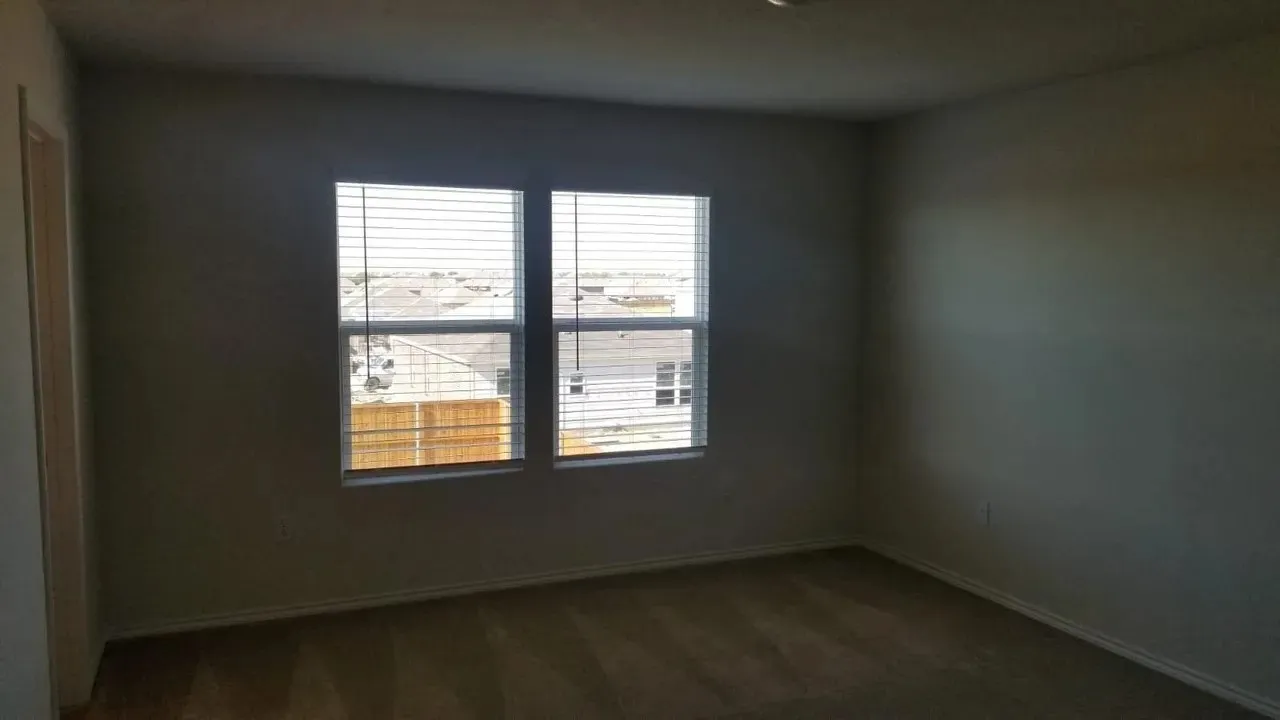 Neutral-toned wall finish with twin windows, horizontal blinds, and carpeting