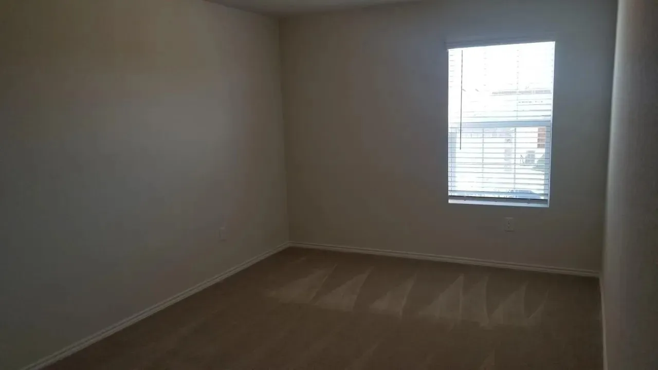 Neutral wall paint, carpeted flooring, and a single window with horizontal blinds