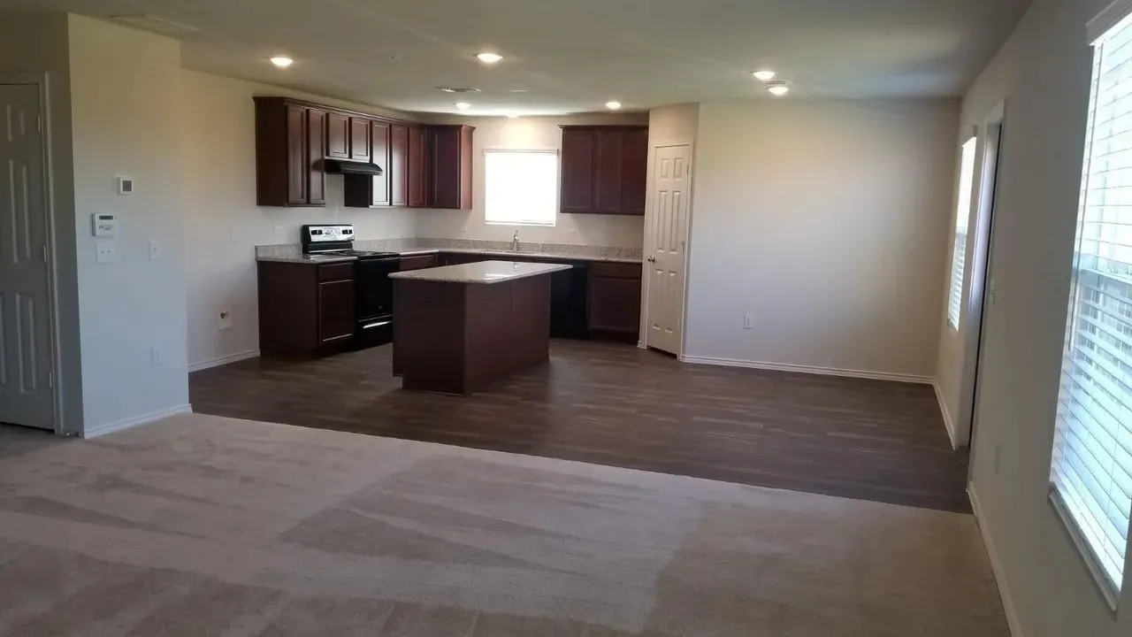 Open-concept living space featuring wood-finish flooring, recessed lighting, and a kitchen with dark cabinetry and a light-toned countertop