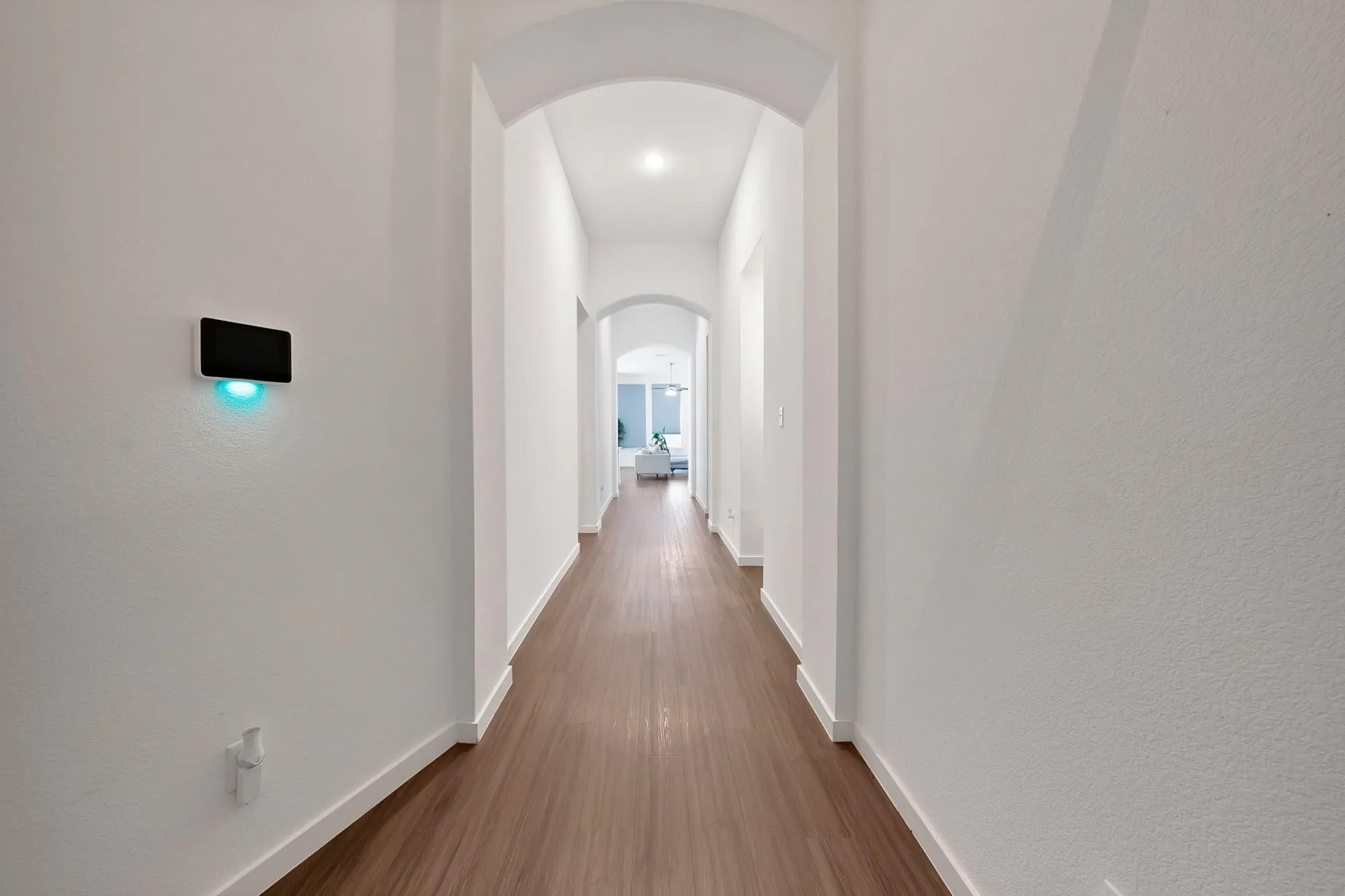 Arched doorways define the hallway, featuring wood-finish flooring and recessed lighting