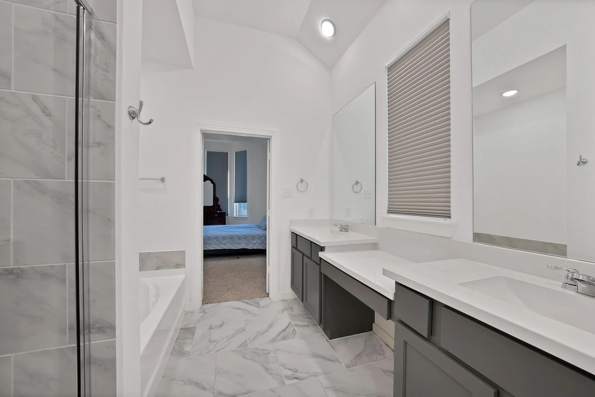 Vanity with dual sinks and ample countertop space, tiled flooring, recessed lighting, and a walk-in shower with glass enclosure