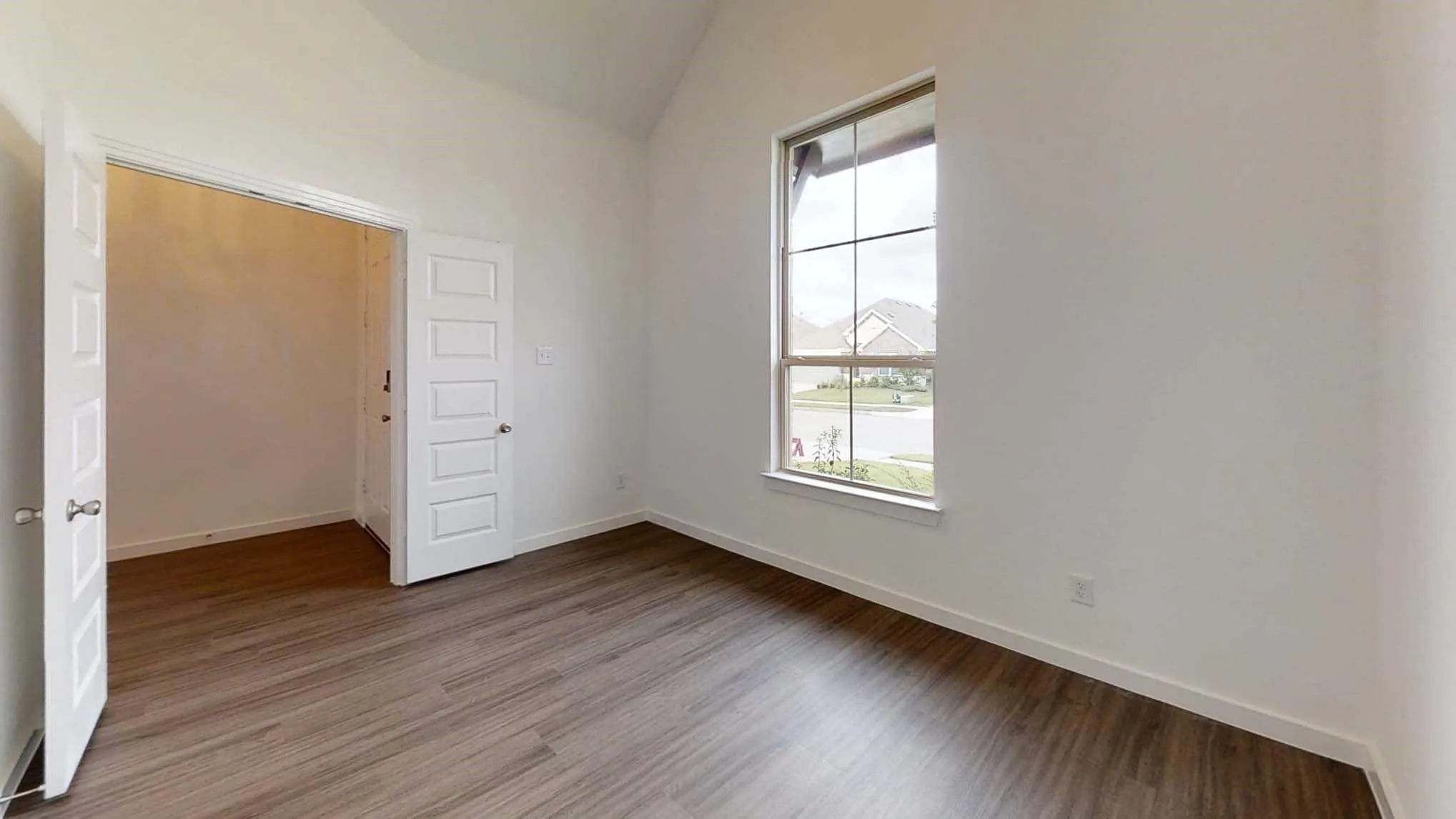 Vaulted ceiling, wood-finish flooring, white walls, and a large window