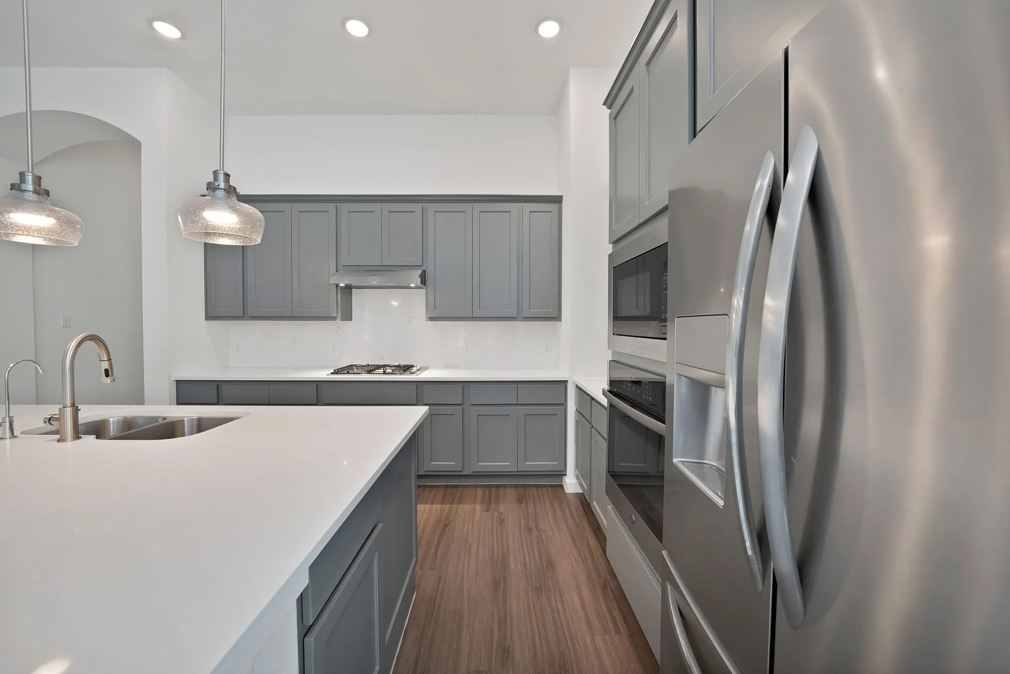 Kitchen featuring gray shaker cabinetry, stainless steel appliances, white countertops, a gas range with a range hood, and wood-finish flooring