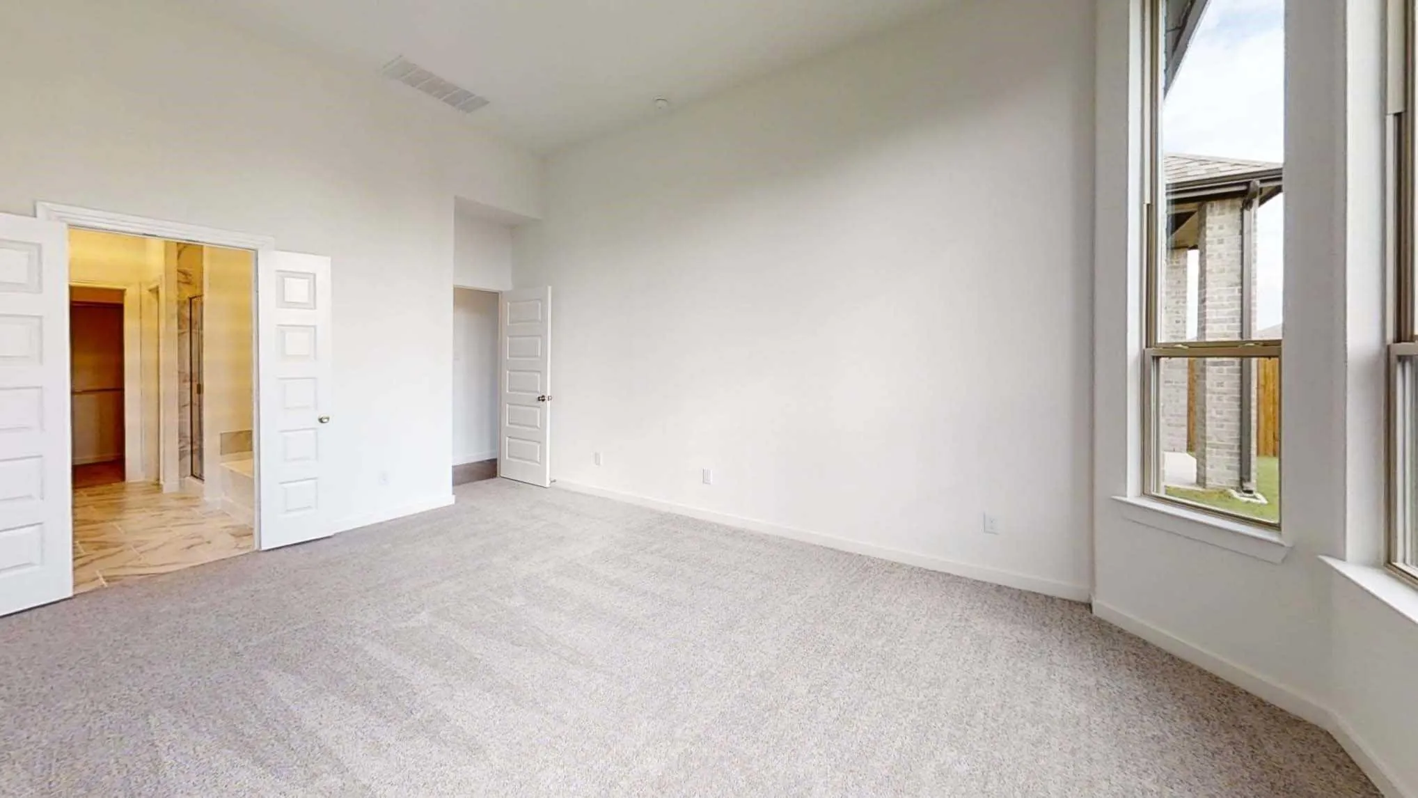 Spacious room featuring light-toned carpeting and tall windows