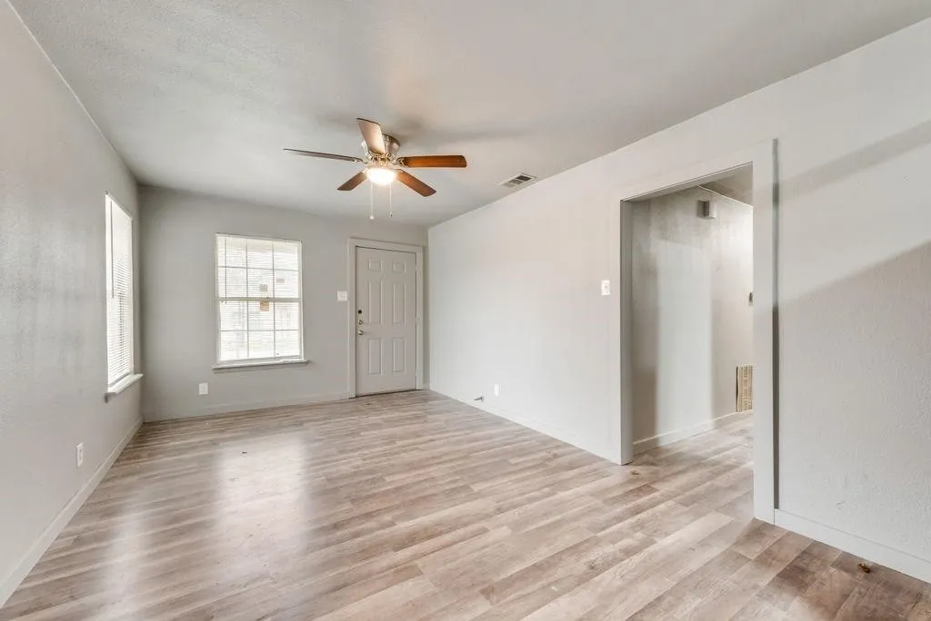 Wood-finish flooring throughout, light gray wall paint, and a ceiling fan with integrated lighting