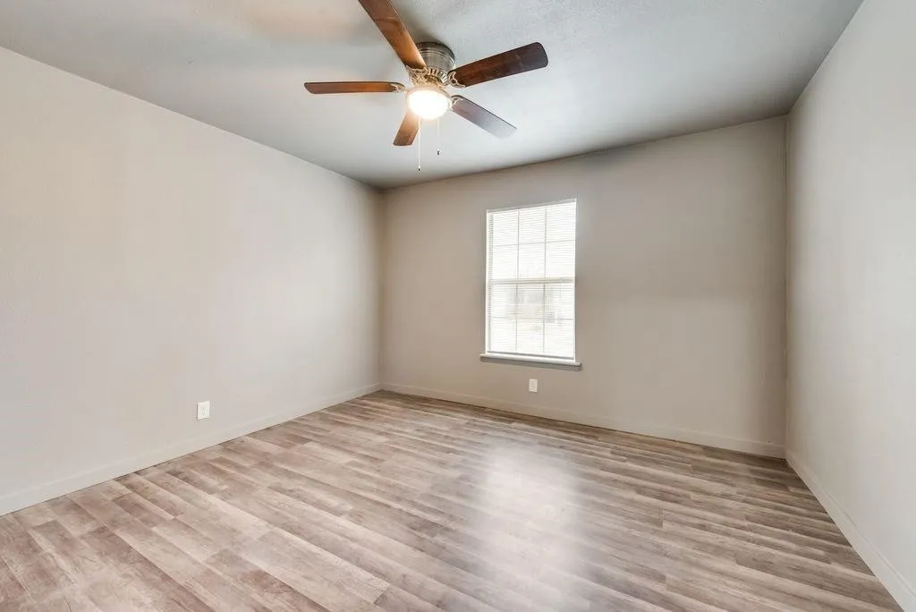 Neutral wall color, wood-finish flooring, ceiling fan, and a single window