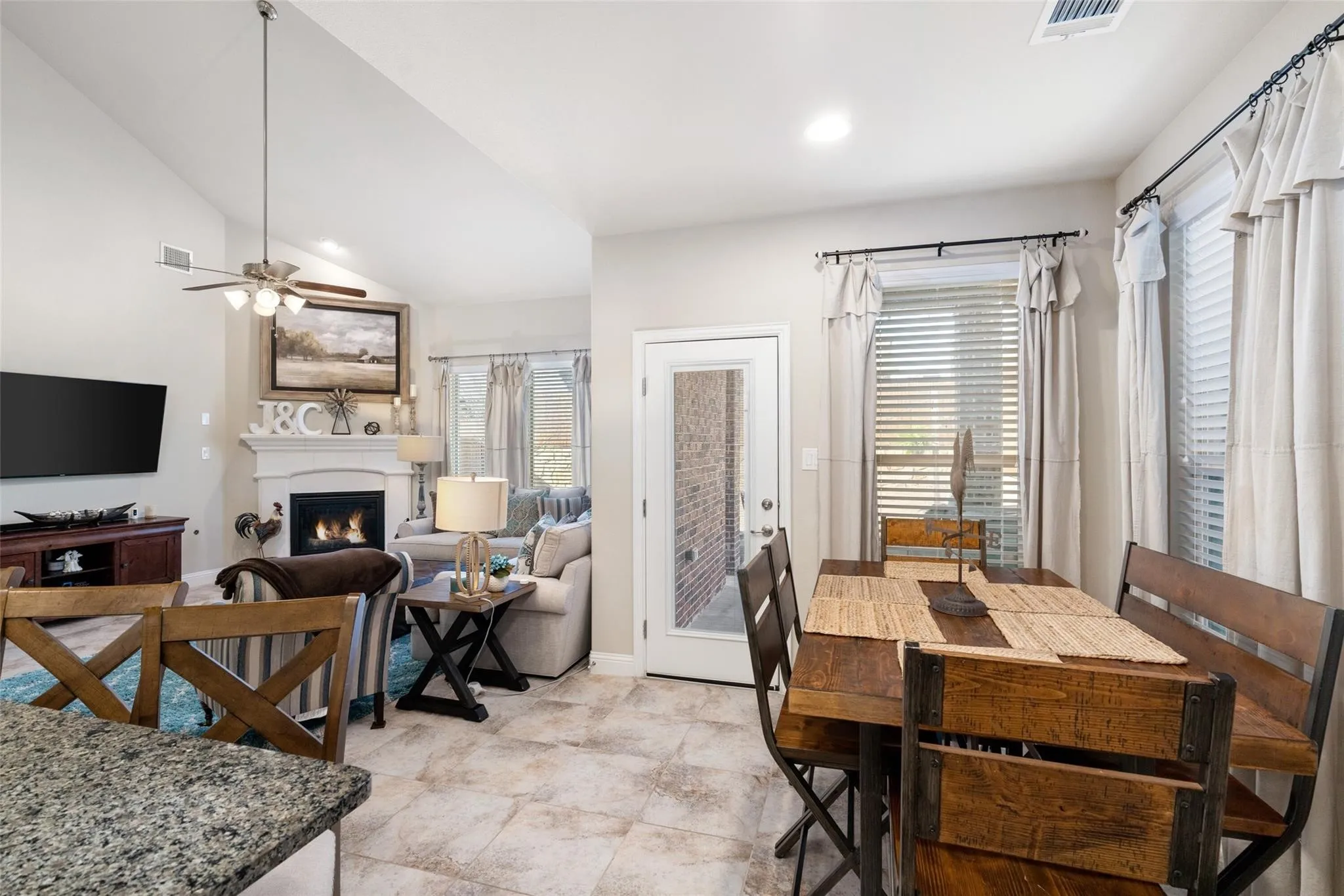 Vaulted ceiling, recessed lighting, tile flooring, built-in fireplace, and a glass-paneled door