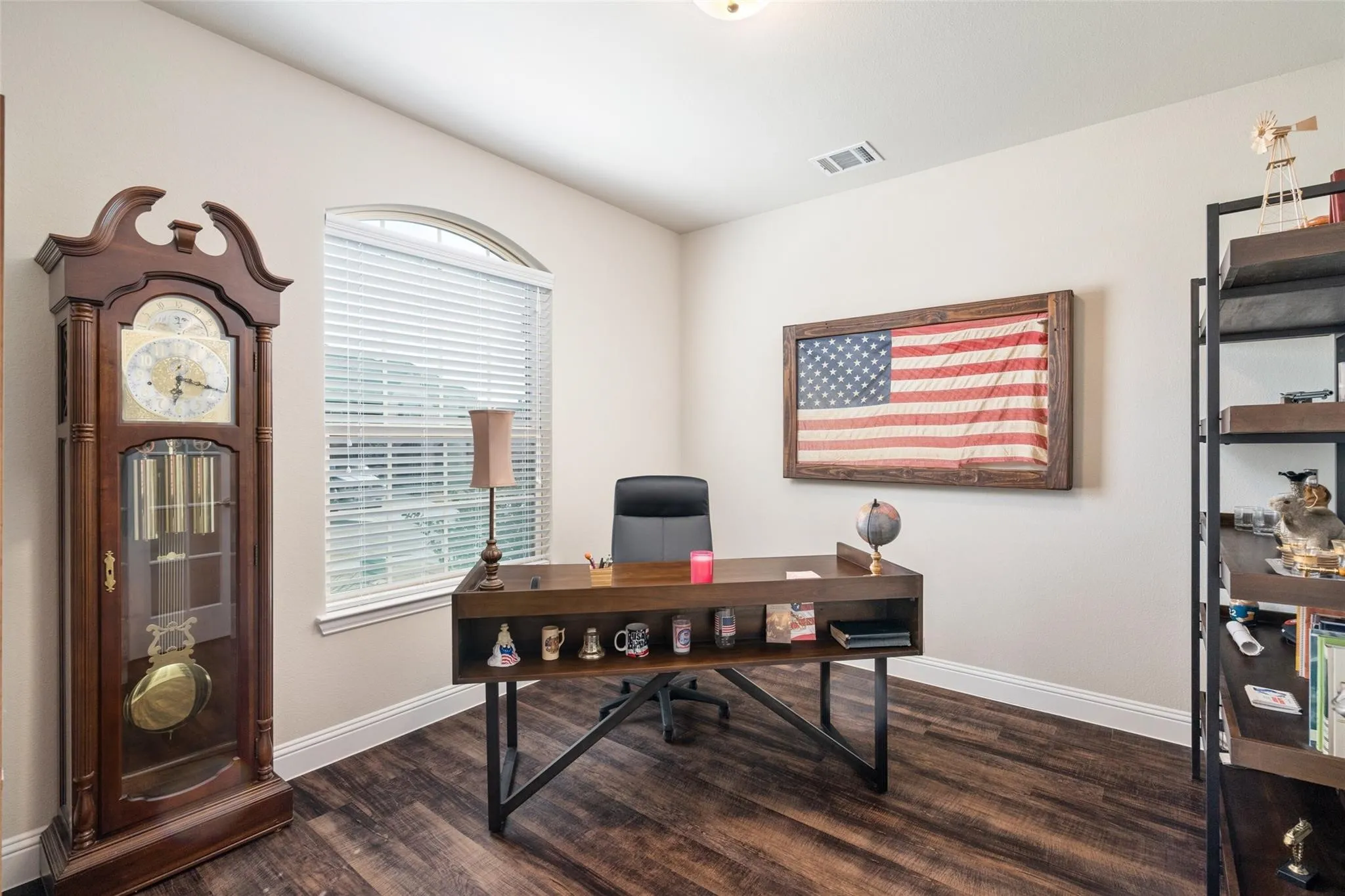 Arch-top window with blinds, wood-finish flooring, and crown molding