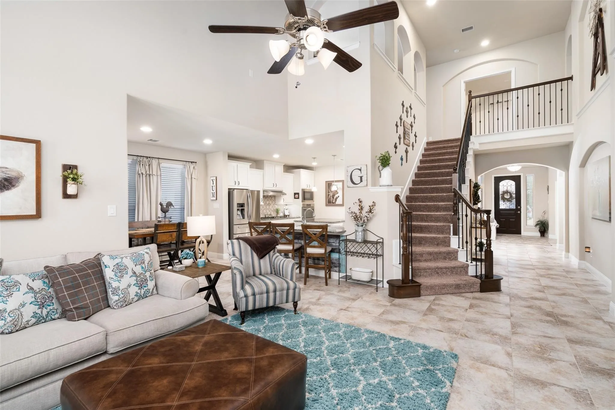 Two-story foyer with tile flooring, grand staircase with wrought iron balusters, and arched doorways