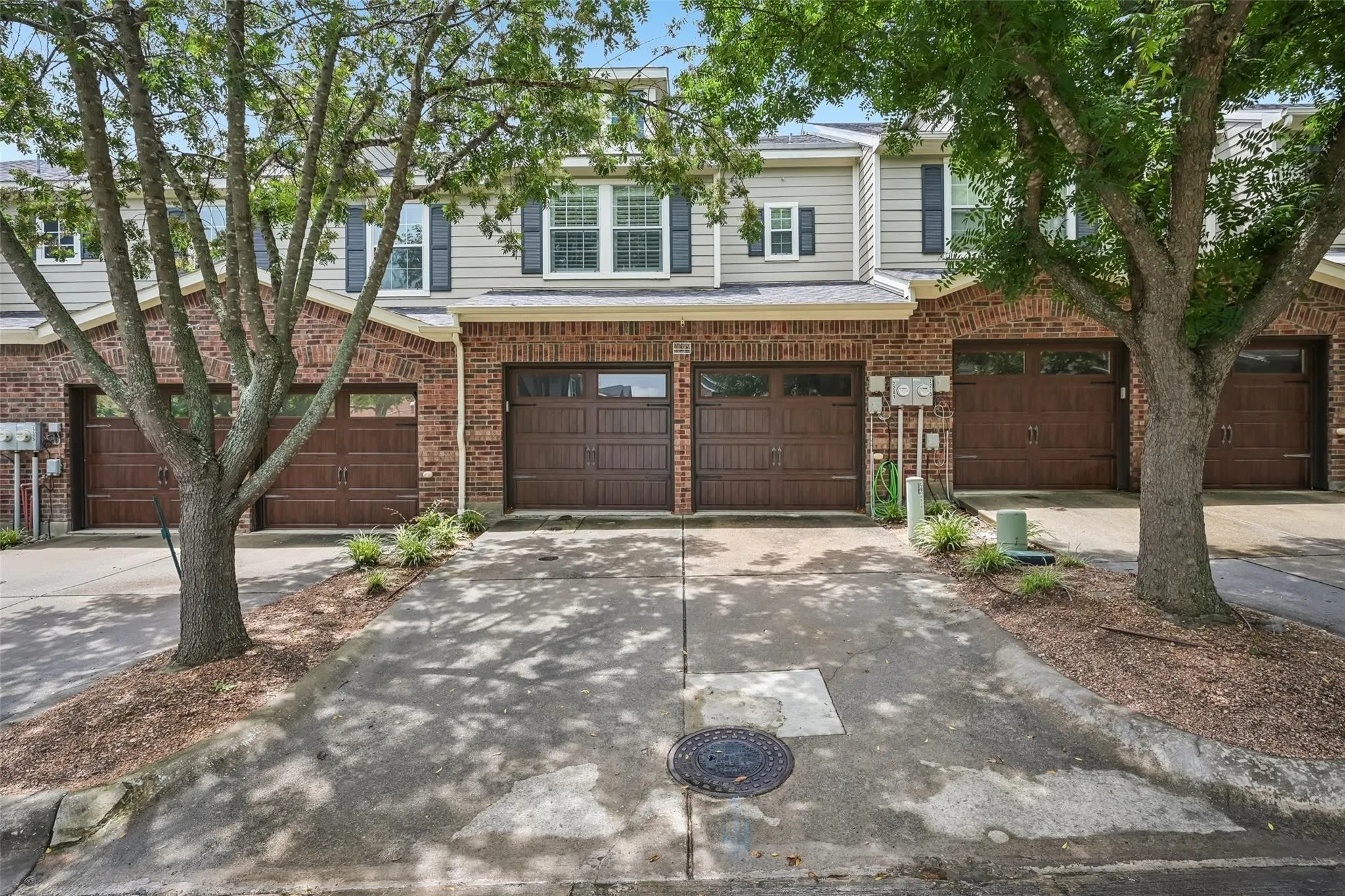 Brick and siding exterior with individual garages and concrete driveways