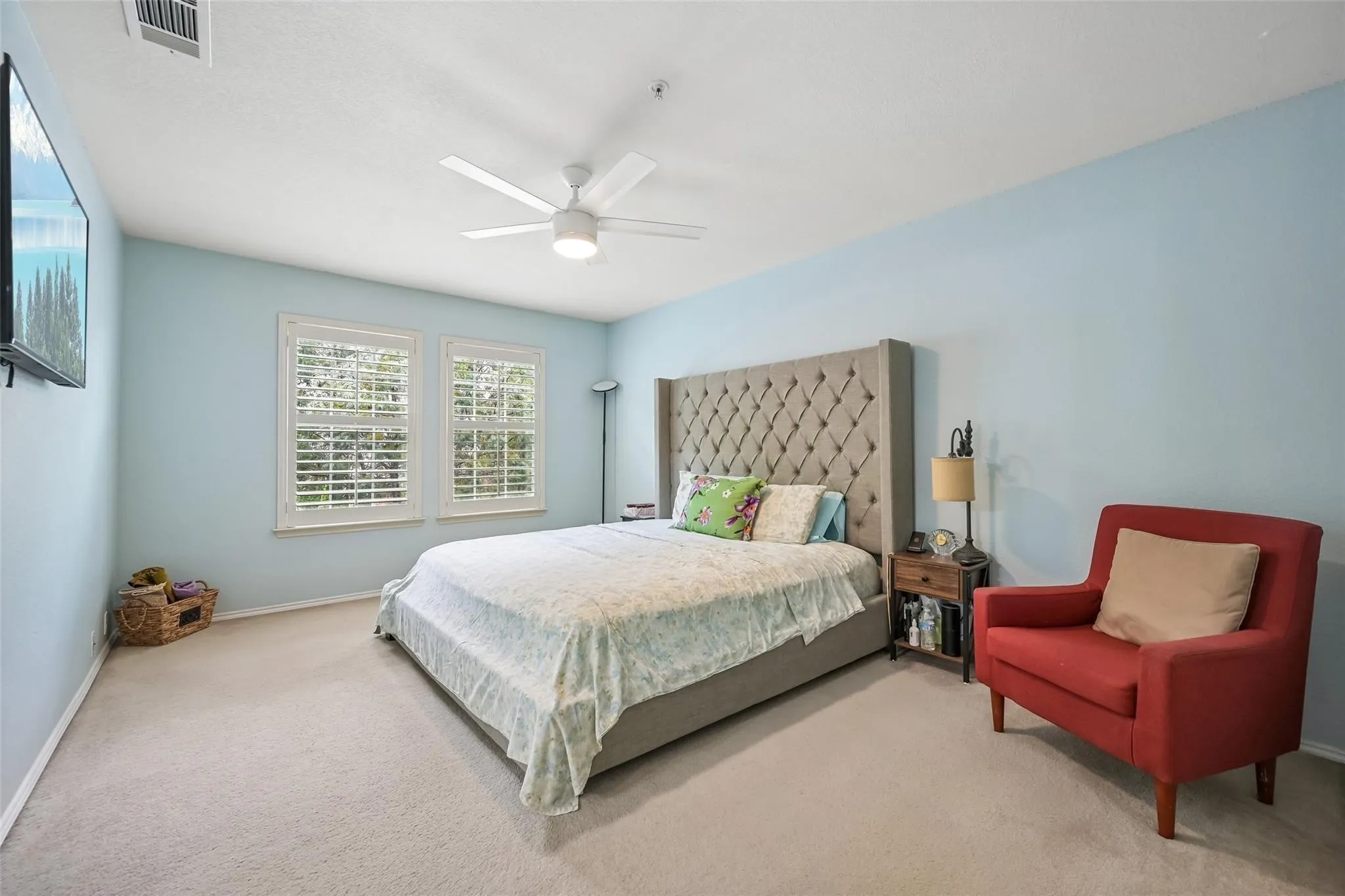Recessed lighting, ceiling fan, two windows with plantation shutters, light blue painted walls, and carpet flooring