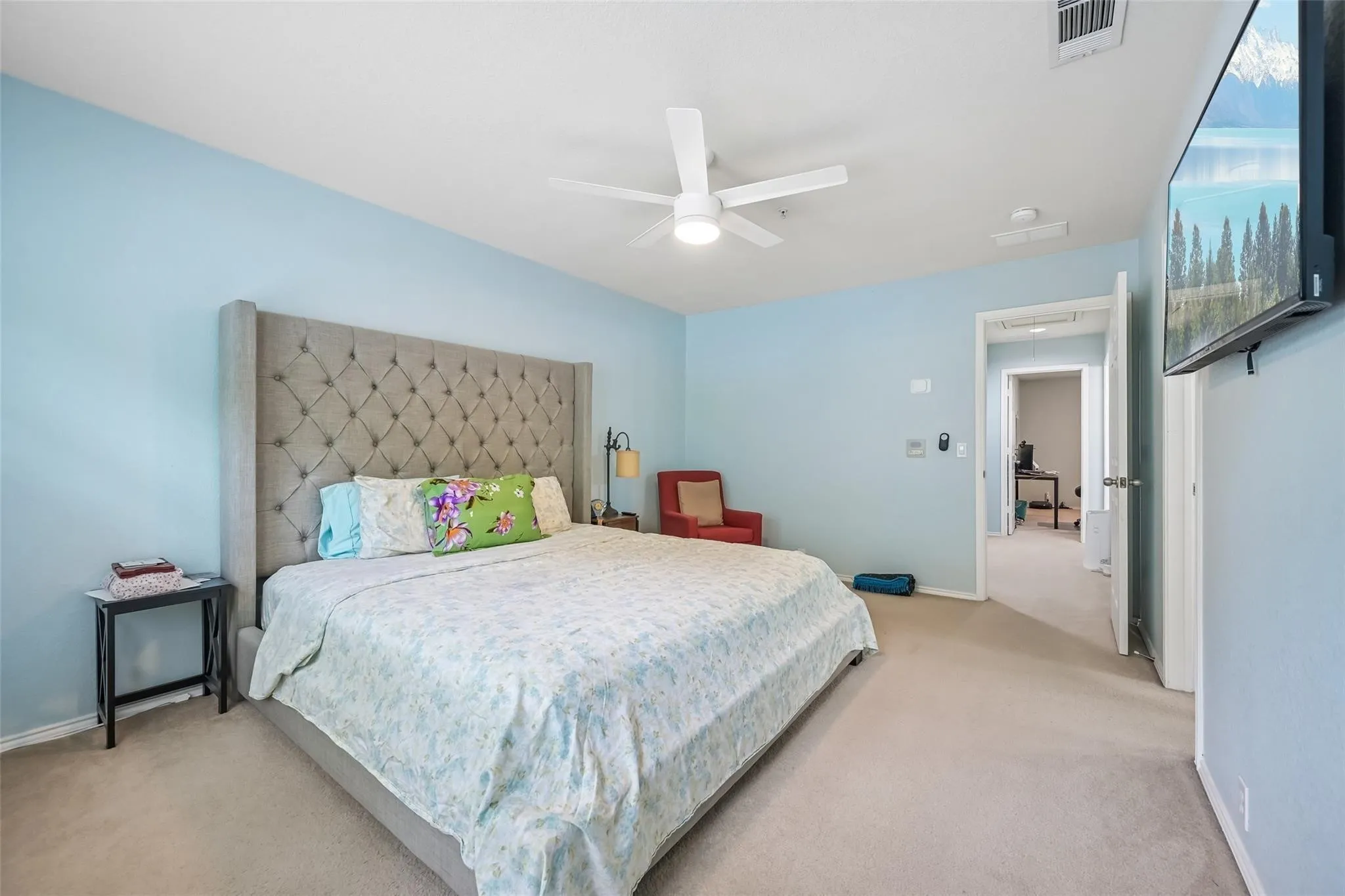 Carpeted flooring throughout, light blue wall paint, and a ceiling fan with integrated lighting