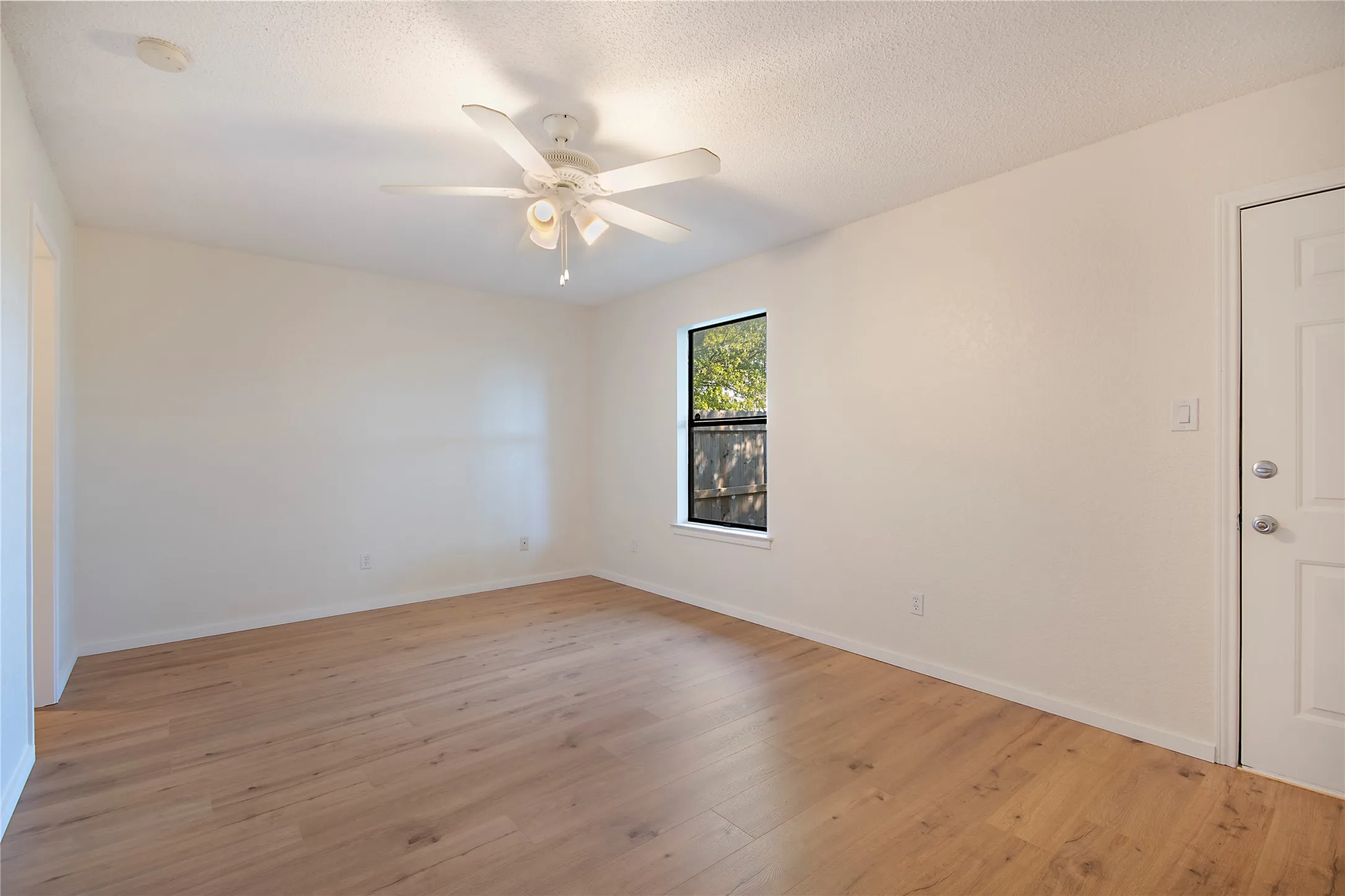 Wood-finish flooring, single window, white ceiling fan, and white painted walls