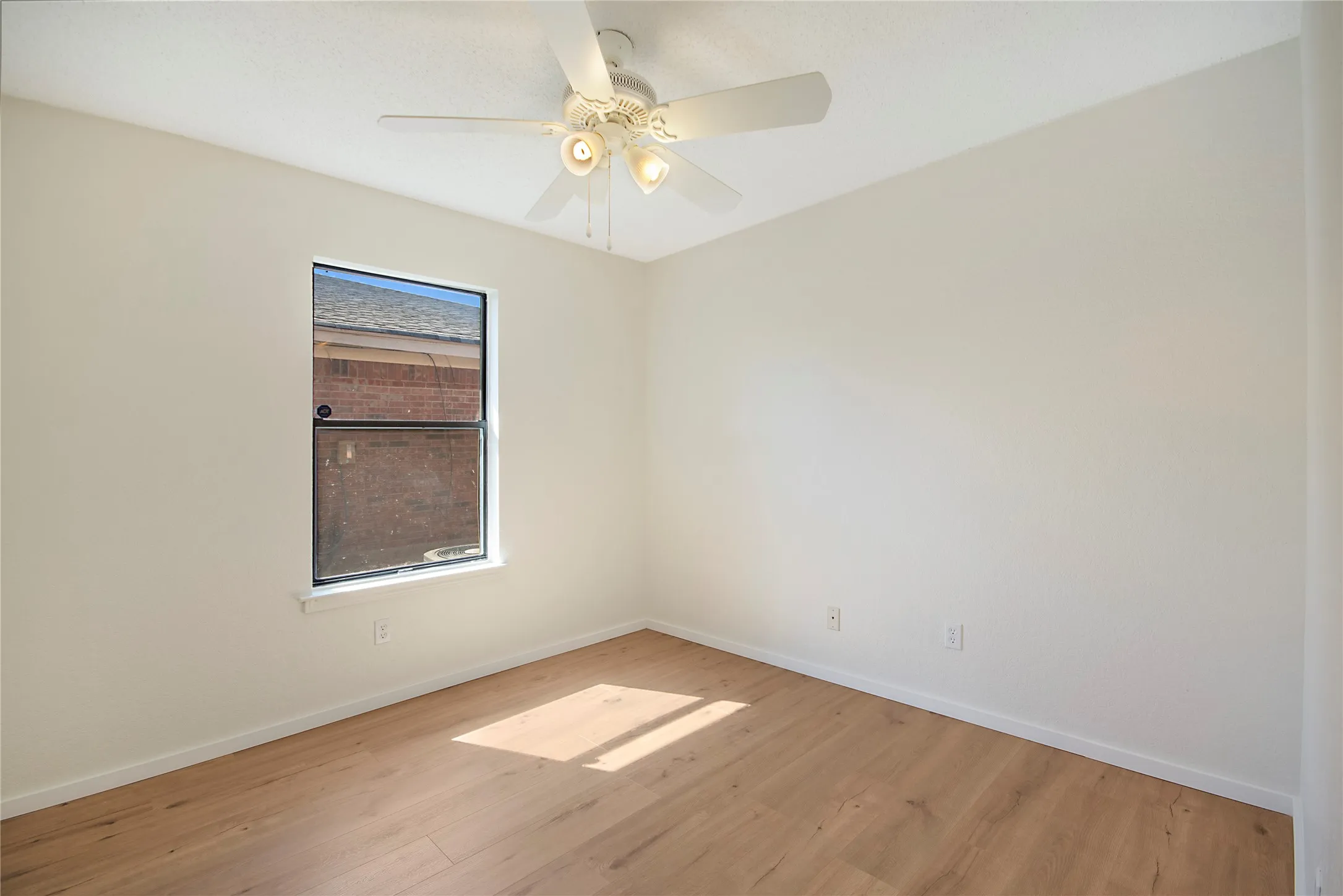 Recessed window with white trim, wood-finish flooring, and a ceiling fan with integrated lighting
