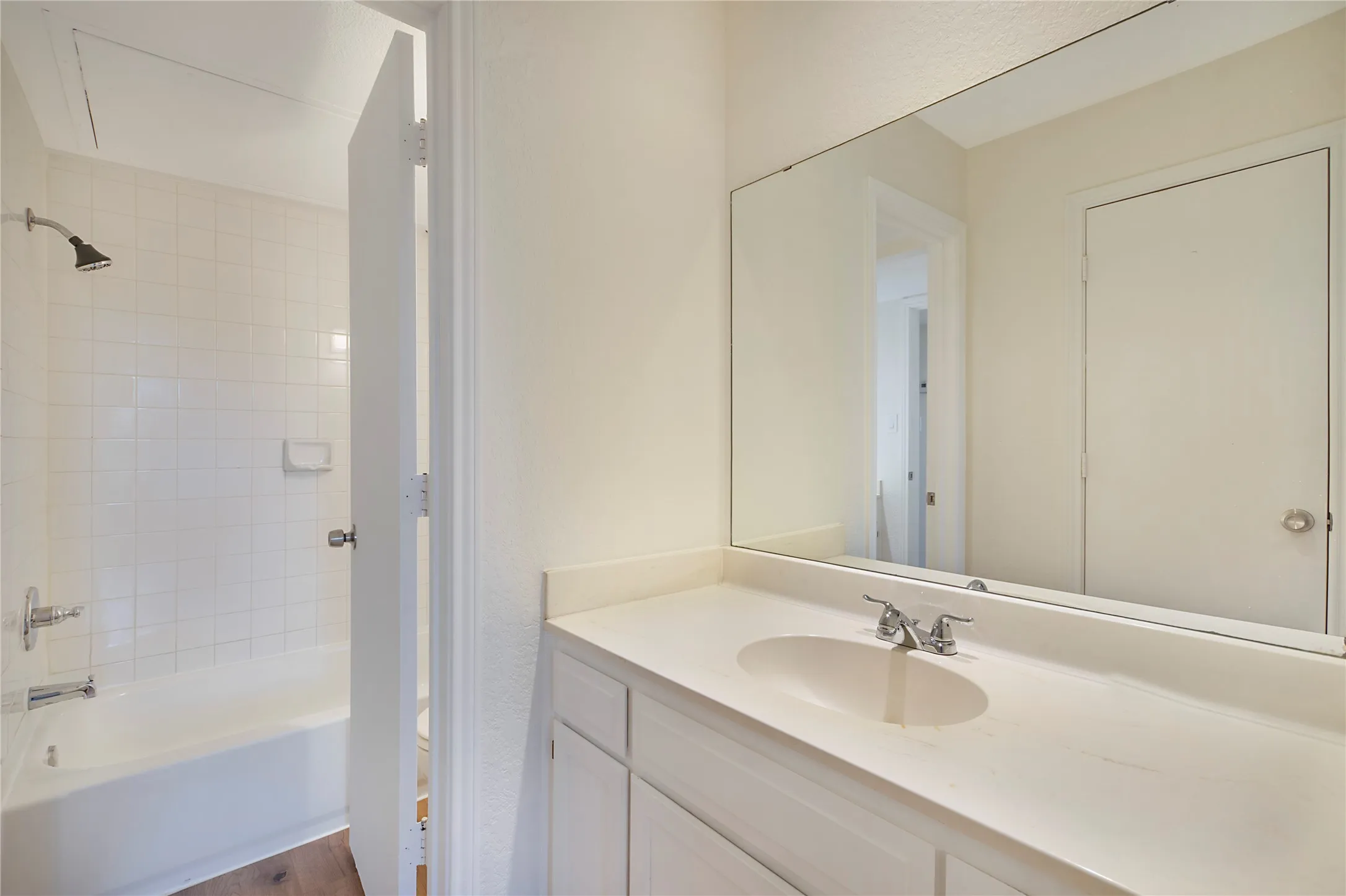 Bathroom vanity with an integrated sink, polished chrome faucet, and expansive mirror