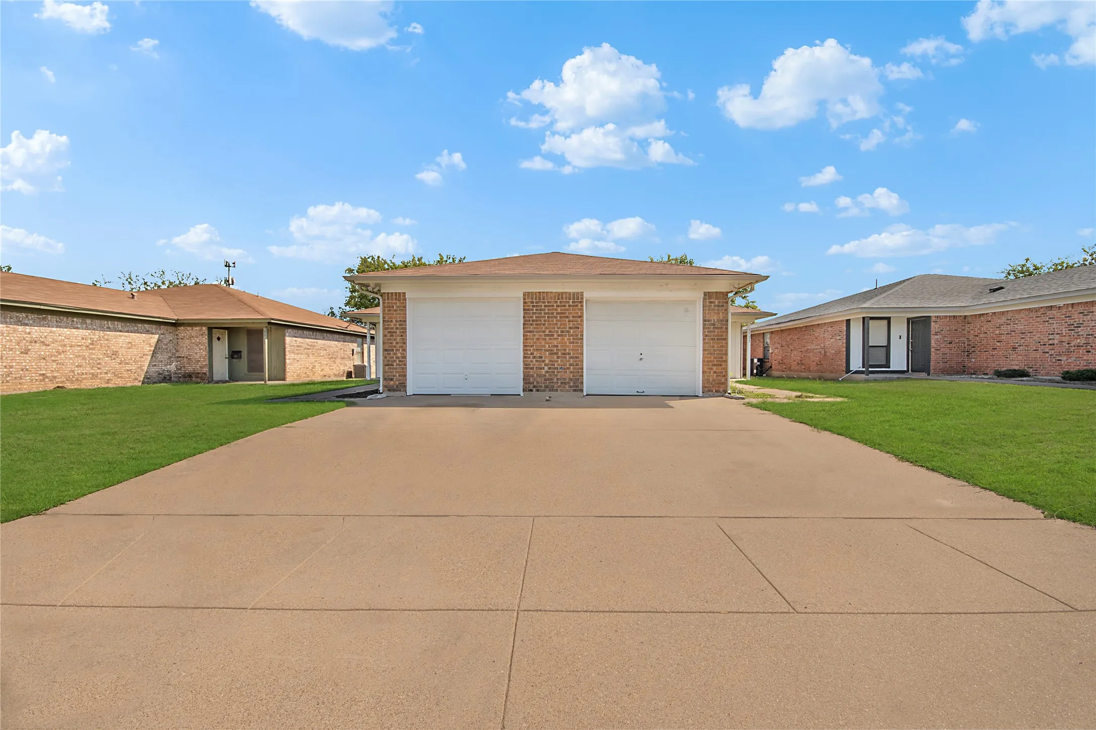 Brick exterior with two white garage doors and a concrete driveway