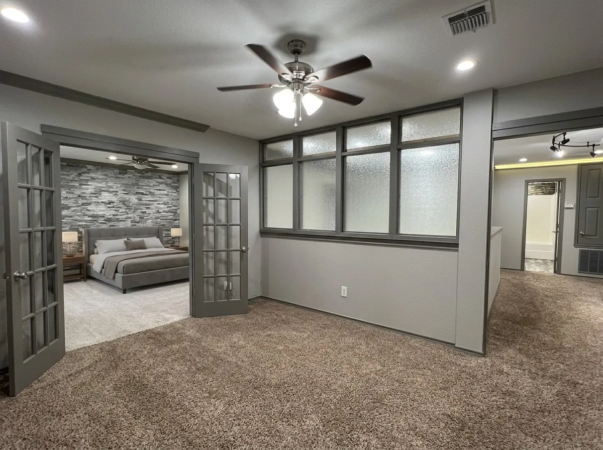 Double French doors with frosted glass panels open to a carpeted room featuring a stone accent wall