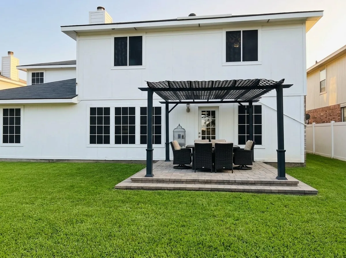 Expansive rear exterior with a structured pergola over a raised paver patio