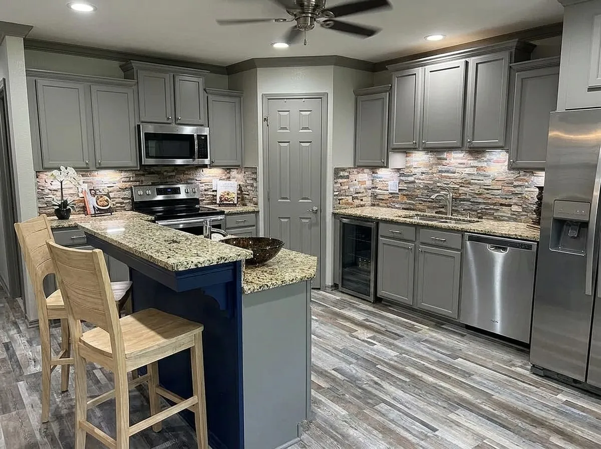Kitchen featuring grey cabinetry, stainless steel appliances, a multi-tone stone backsplash, and granite countertops