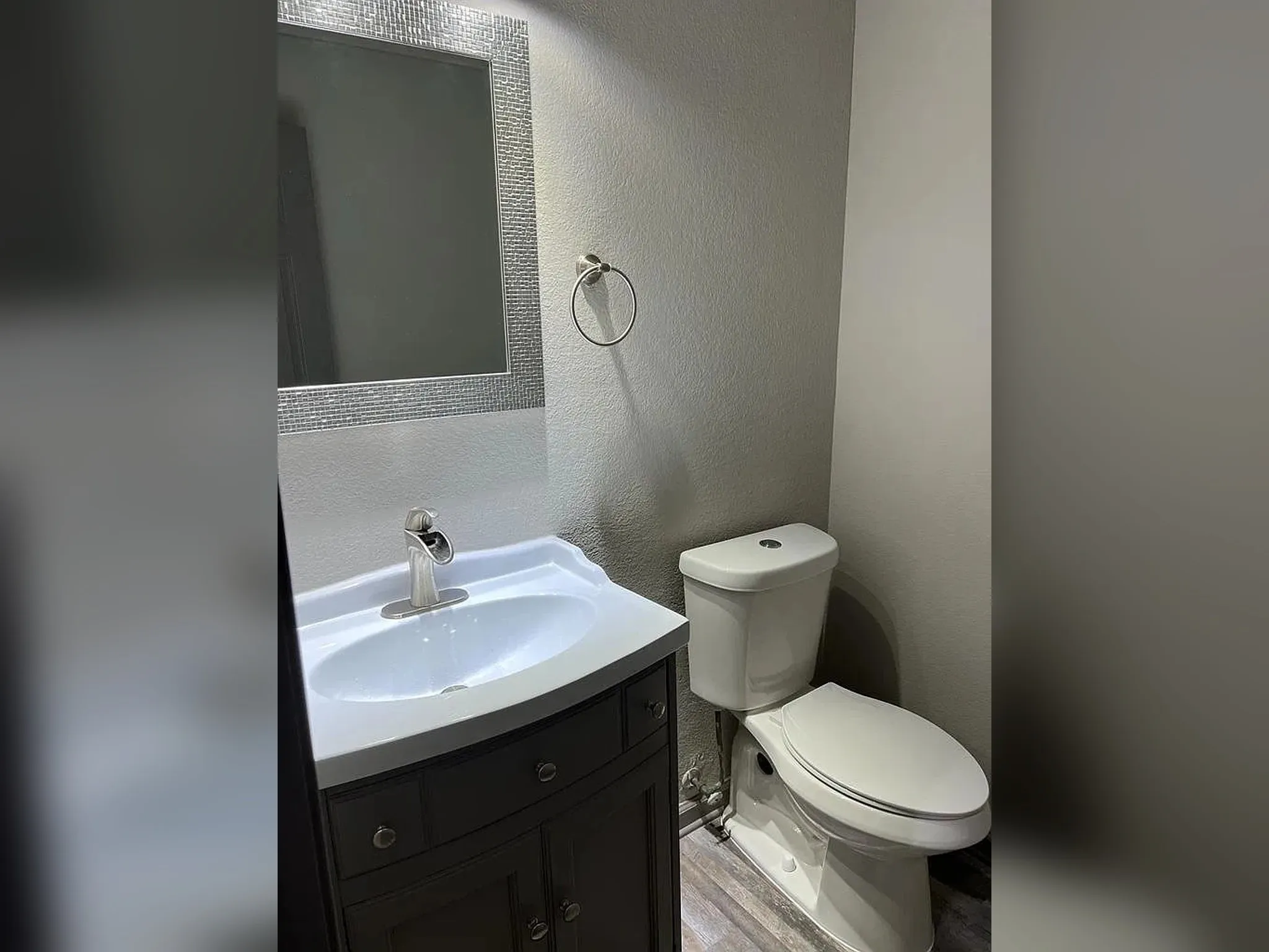 Vanity with under-sink storage, decorative mirror, modern single-handle faucet, and wood-finish flooring