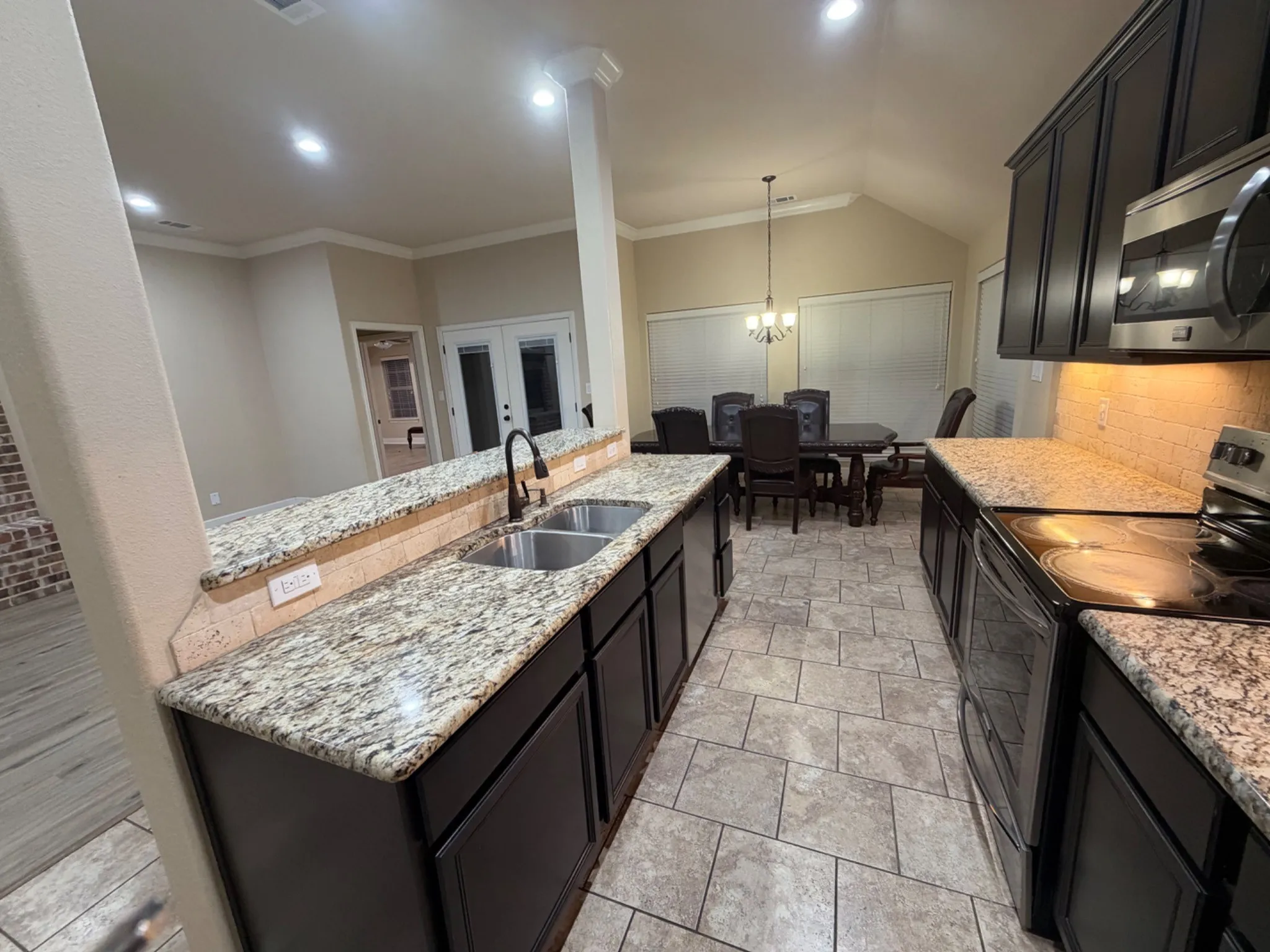 Kitchen with dark cabinetry, speckled countertops, stainless steel appliances, and a tile backsplash