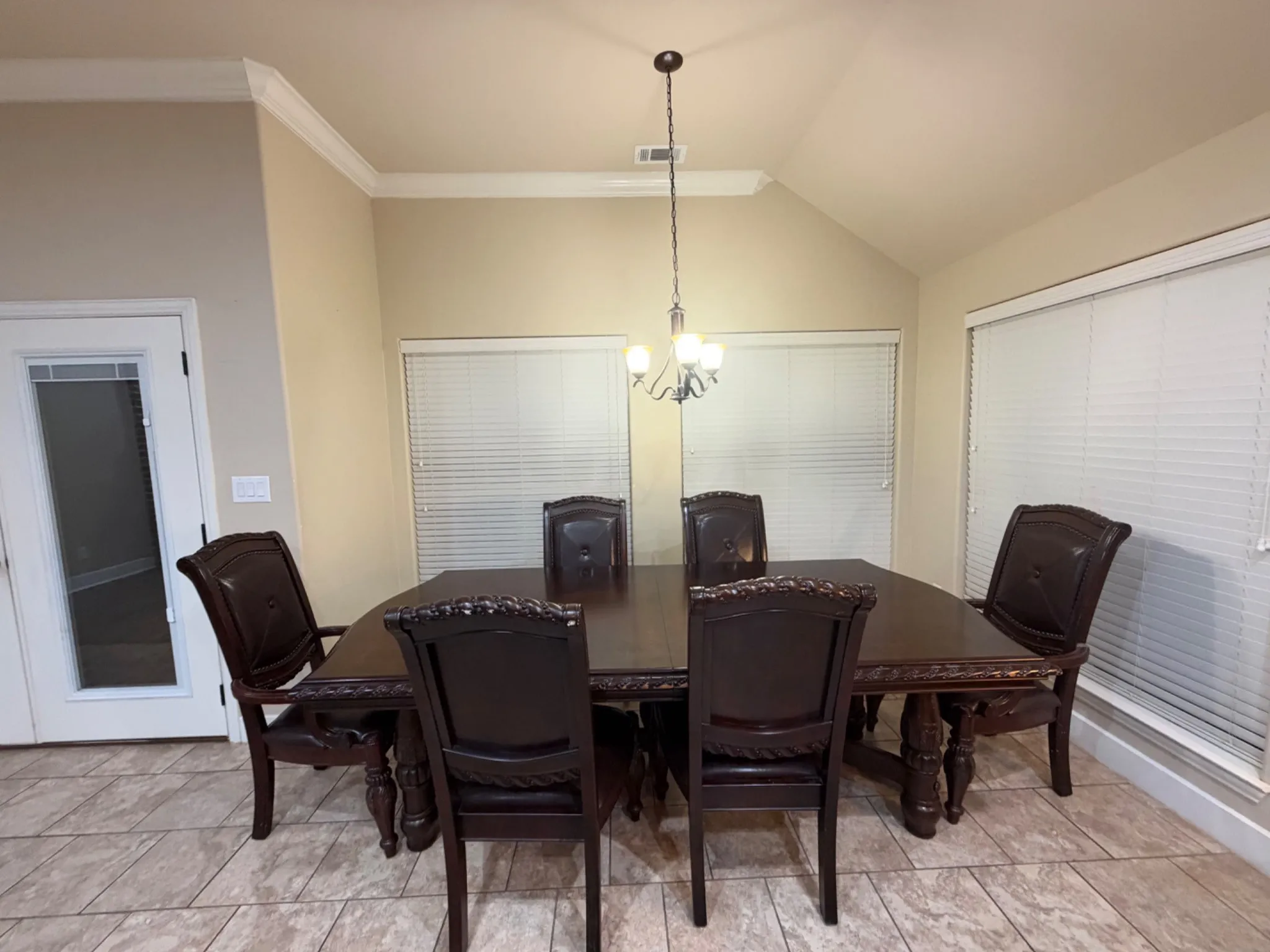 Vaulted ceiling with crown molding, durable tile flooring, and multiple windows