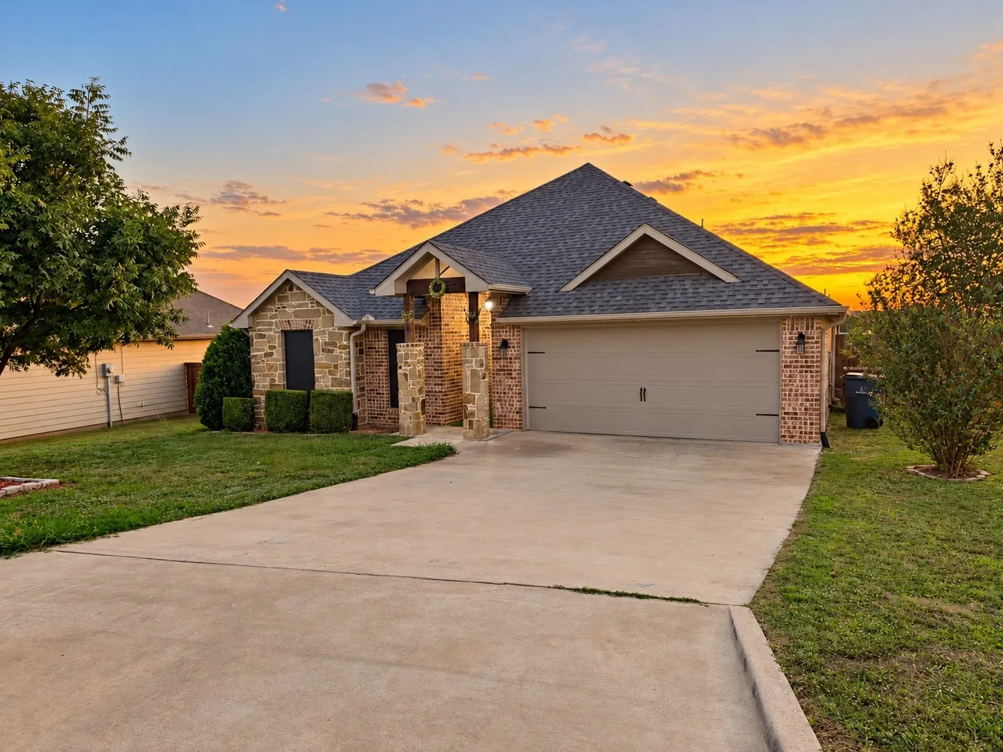 Stone and brick exterior with a gabled roofline, concrete driveway, and attached garage