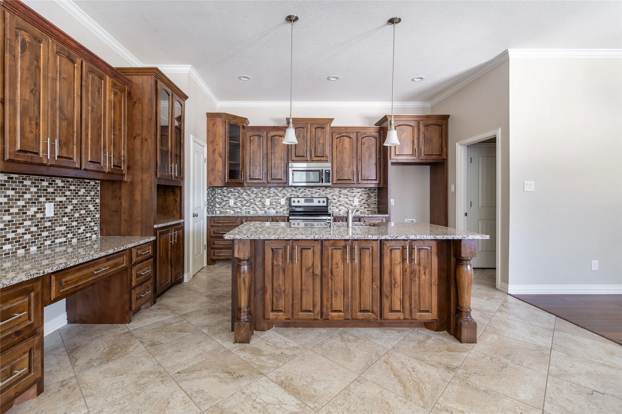 Spacious kitchen featuring an expansive island, rich wood cabinetry, stone countertops, mosaic tile backsplash, and stainless steel appliances