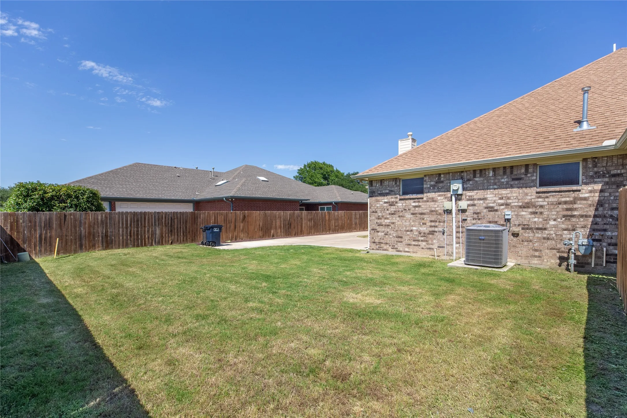 Expansive backyard featuring a manicured lawn and wood privacy fence