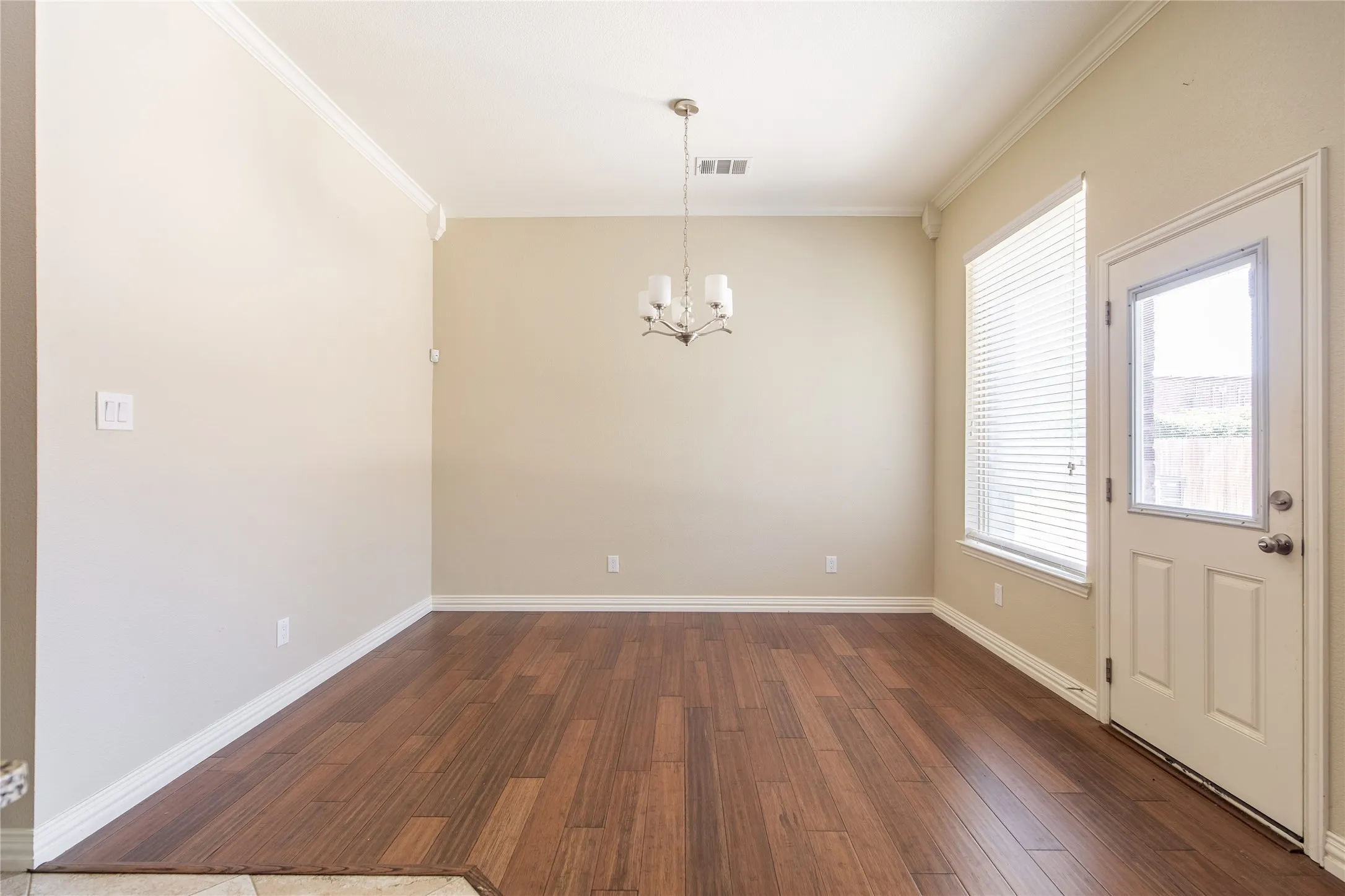 Wood-finish flooring, crown molding, white trim, and a contemporary chandelier