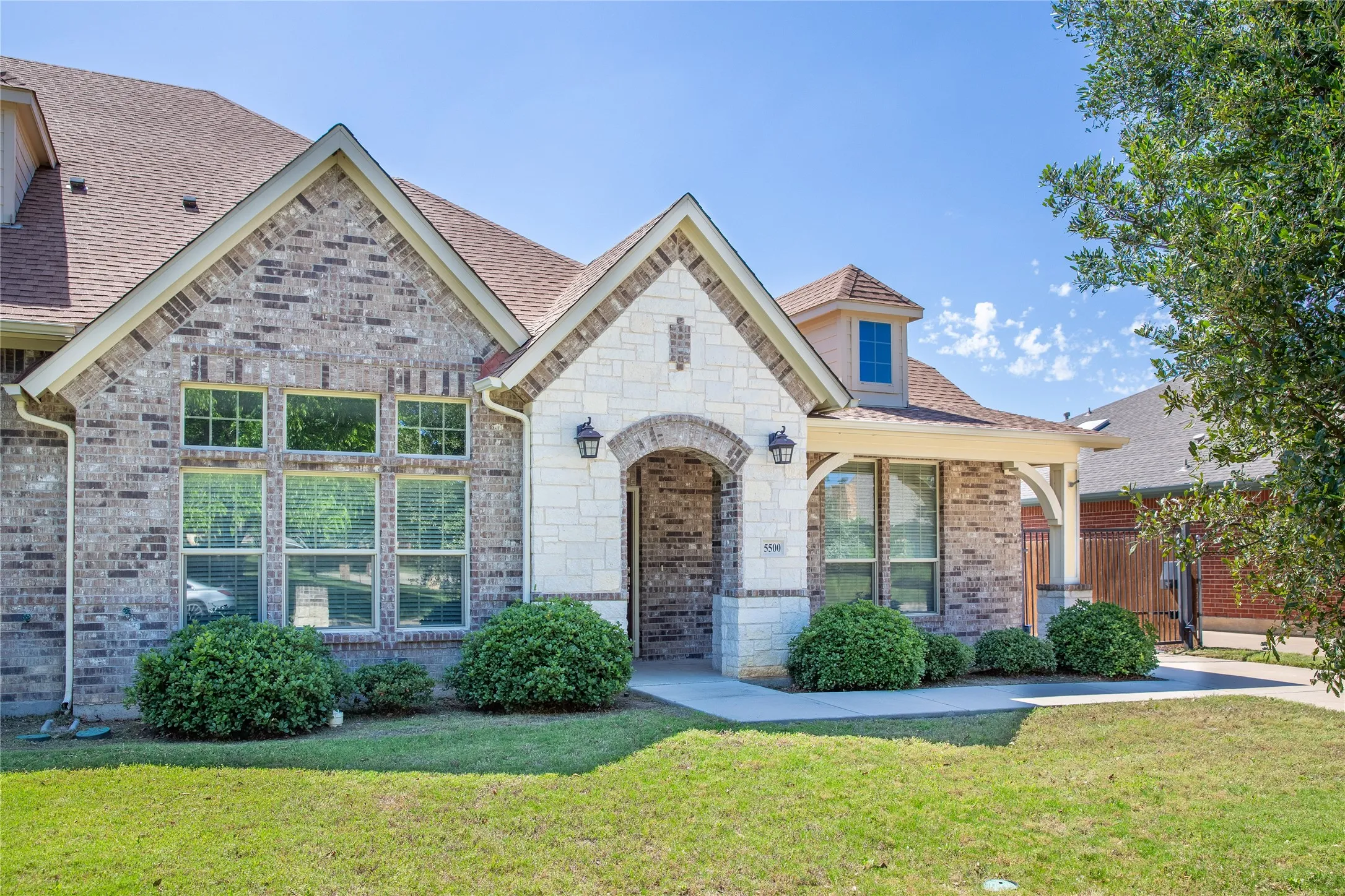 Brick and stone exterior featuring an arched entryway, multiple gables, and a dormer window