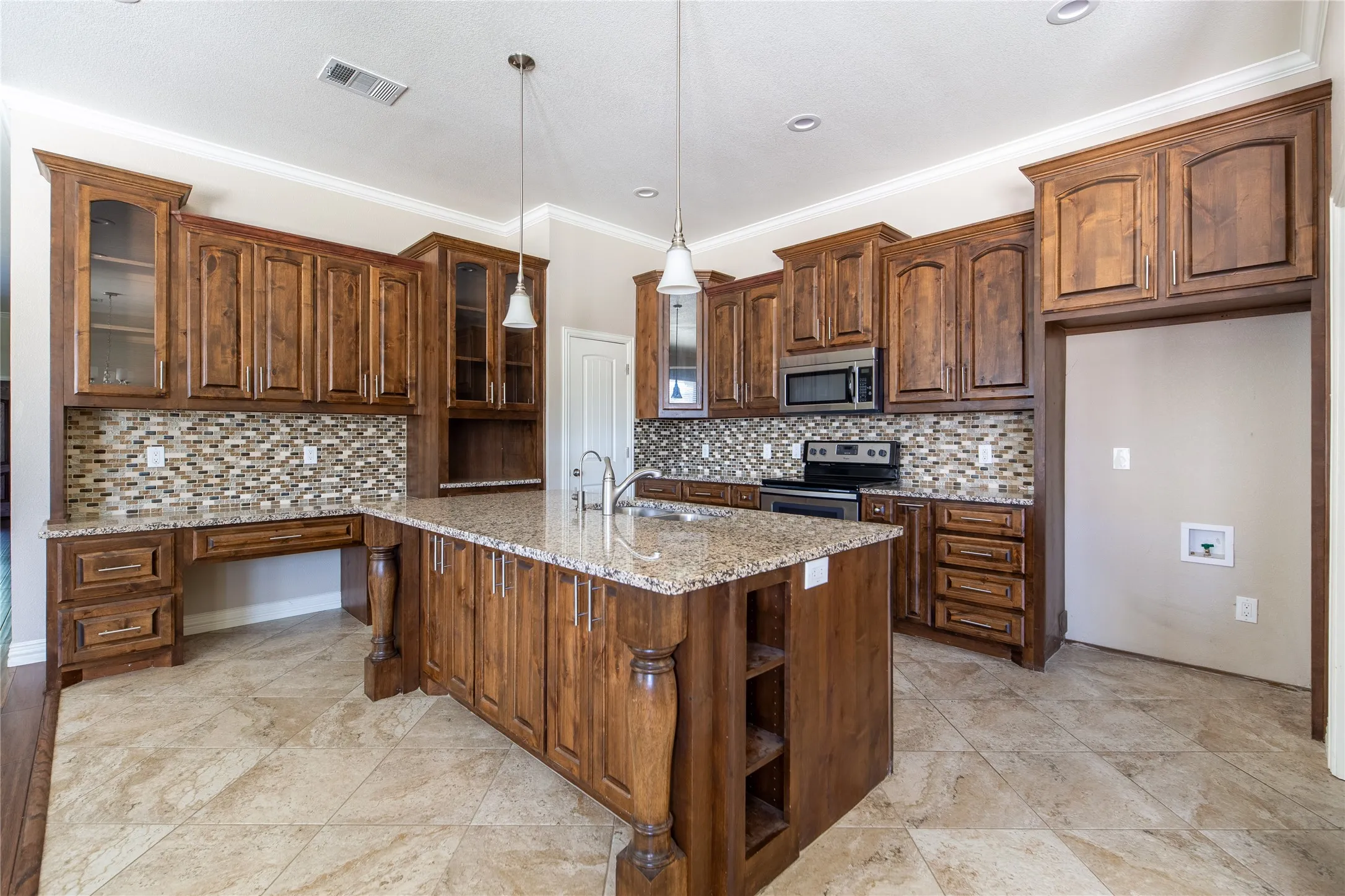 Spacious kitchen featuring extensive wood-finish cabinetry, a large center island with a sink, stone countertops, stainless steel appliances, and a mosaic tile backsplash