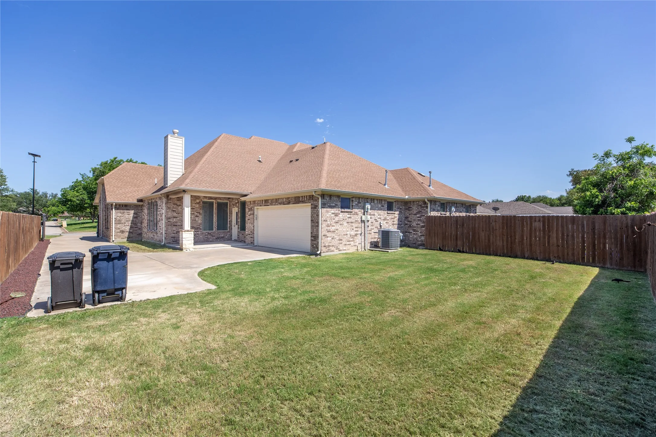 Brown brick exterior with a tan shingle roof, attached garage, and a concrete driveway