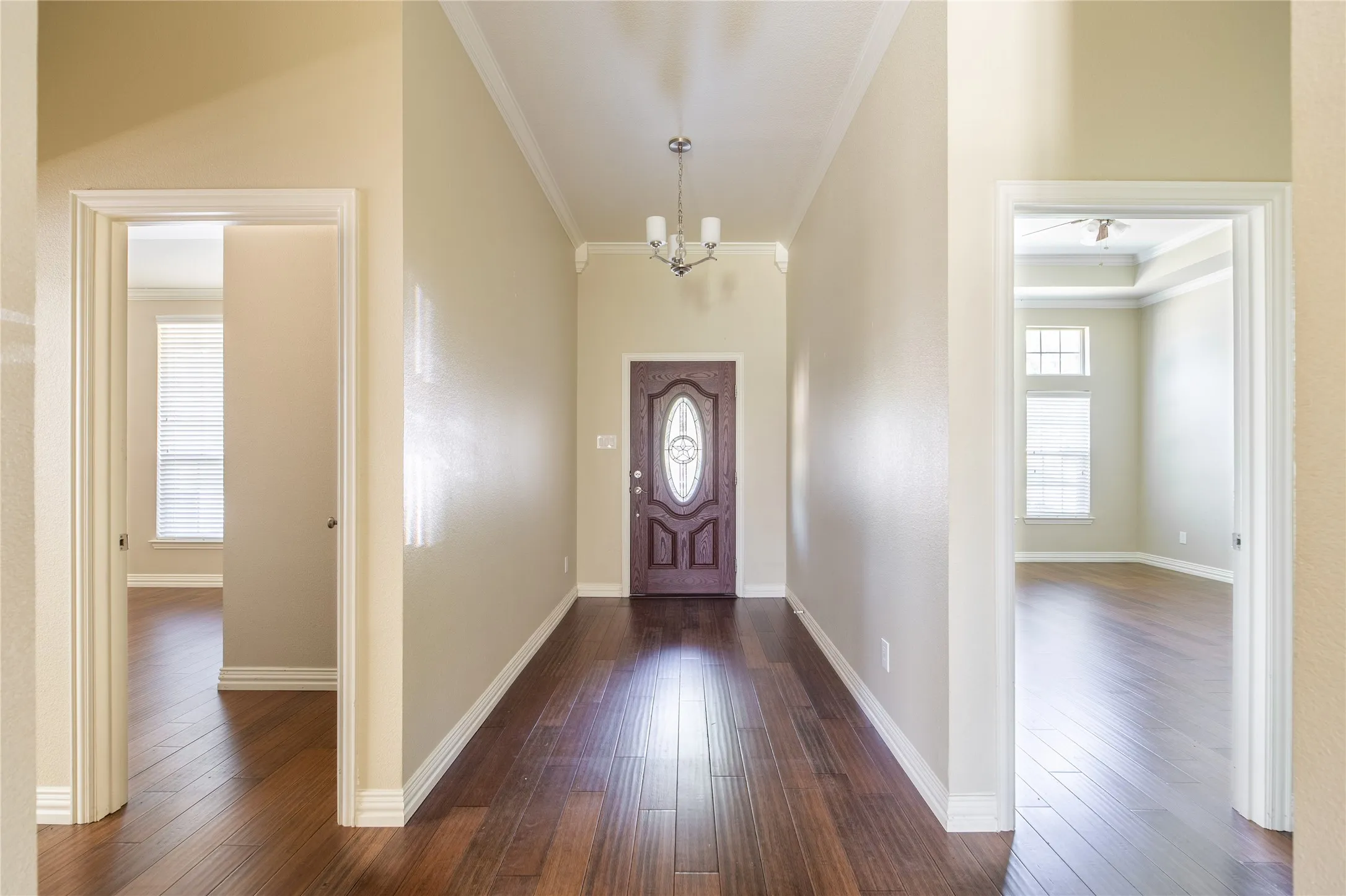 Entryway featuring wood-finish flooring, a decorative front door with an oval glass insert, and a three-light chandelier