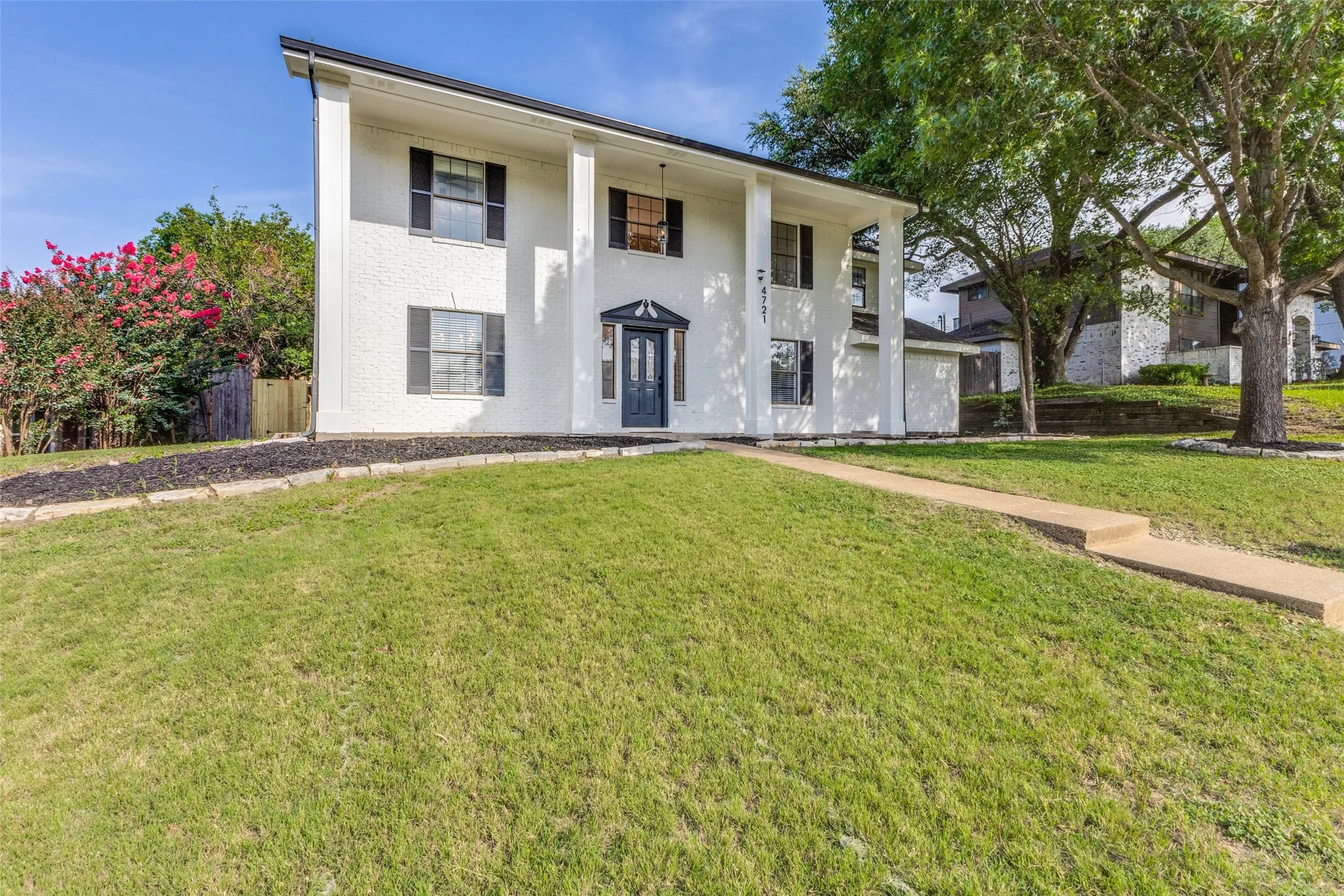 Two-story white brick exterior with black shutters and a prominent front entrance