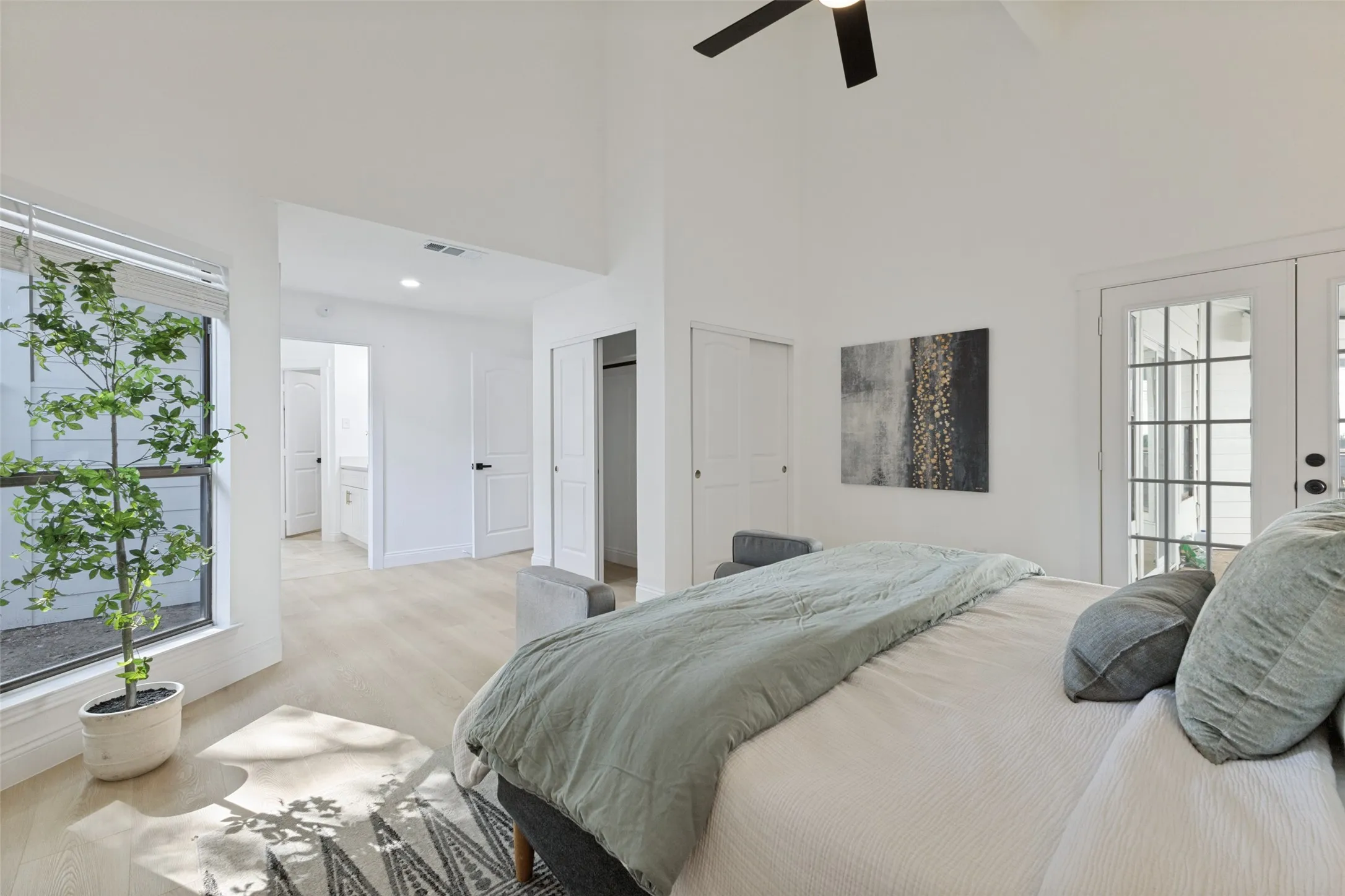 Primary bedroom with a vaulted ceiling, ceiling fan, luxury vinyl plank flooring, and French doors with divided lites