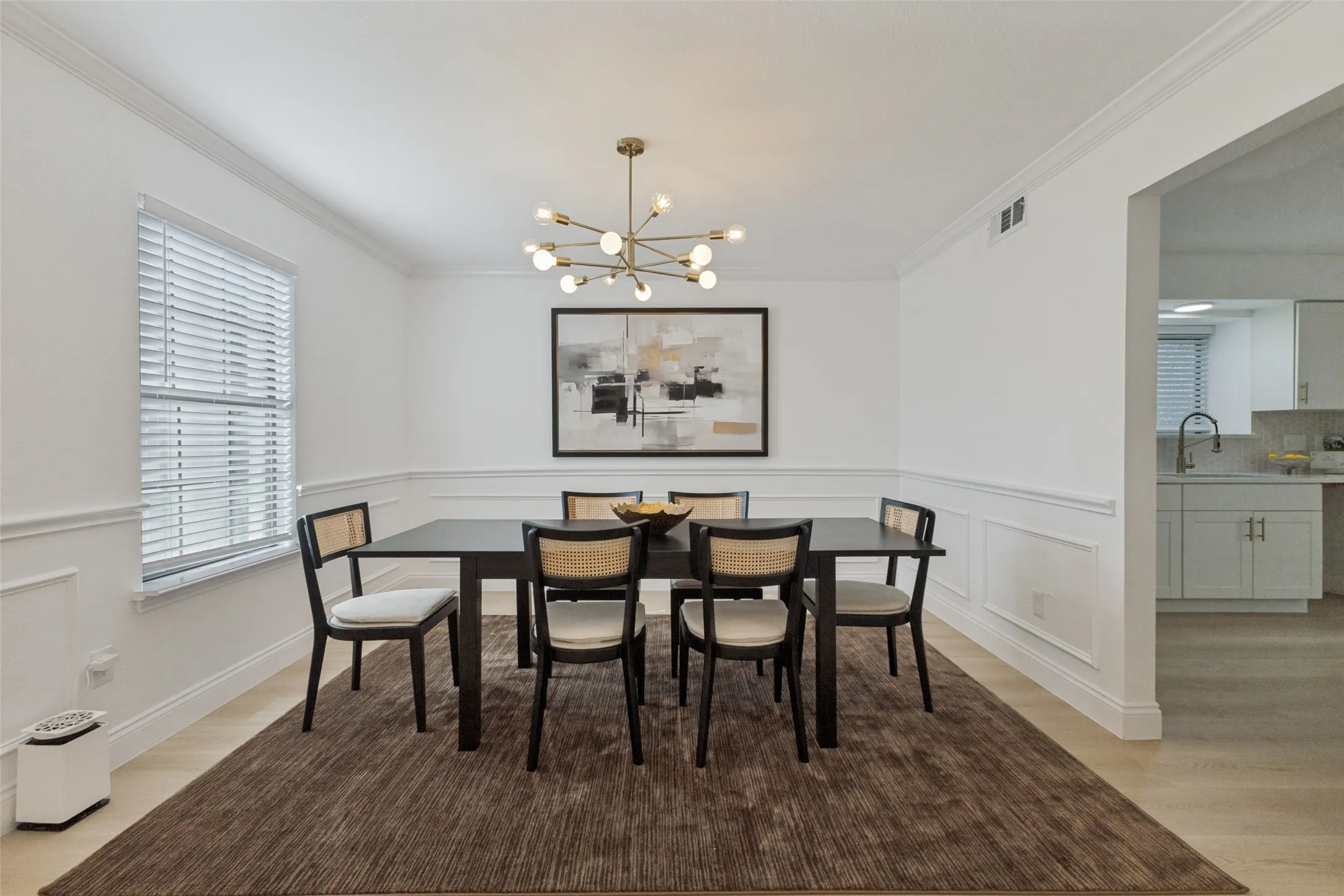 Formal dining area featuring crown molding, wainscoting, luxury vinyl plank flooring, a contemporary chandelier, and a window with blinds