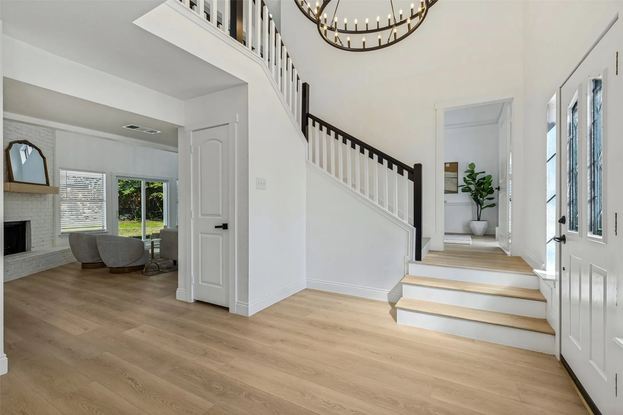 Two-story foyer with luxury vinyl plank flooring, a grand staircase, and an ornate chandelier