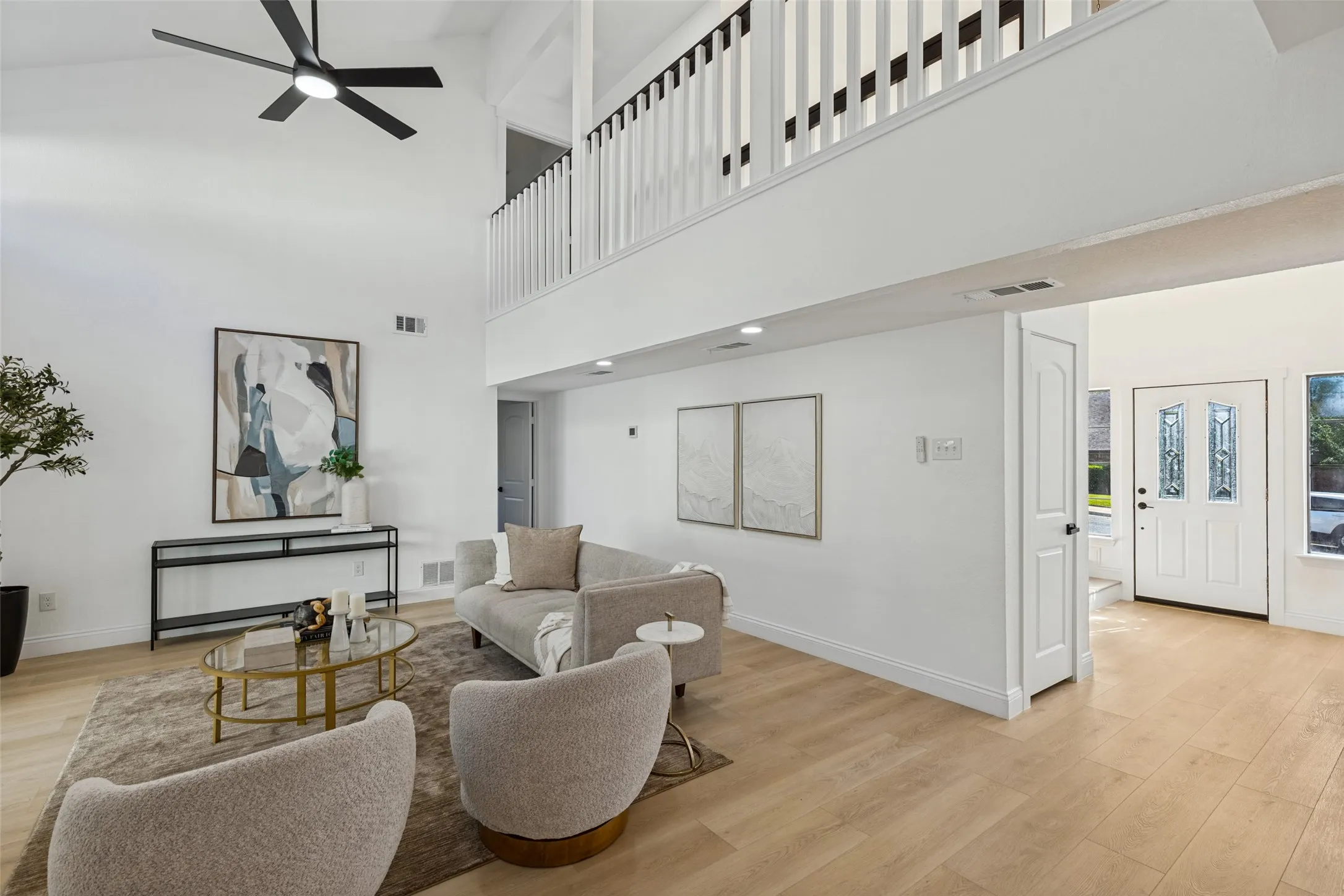 Vaulted ceilings with an overhead fan, luxury vinyl plank flooring, white painted walls, and a prominent white entry door with decorative glass inserts