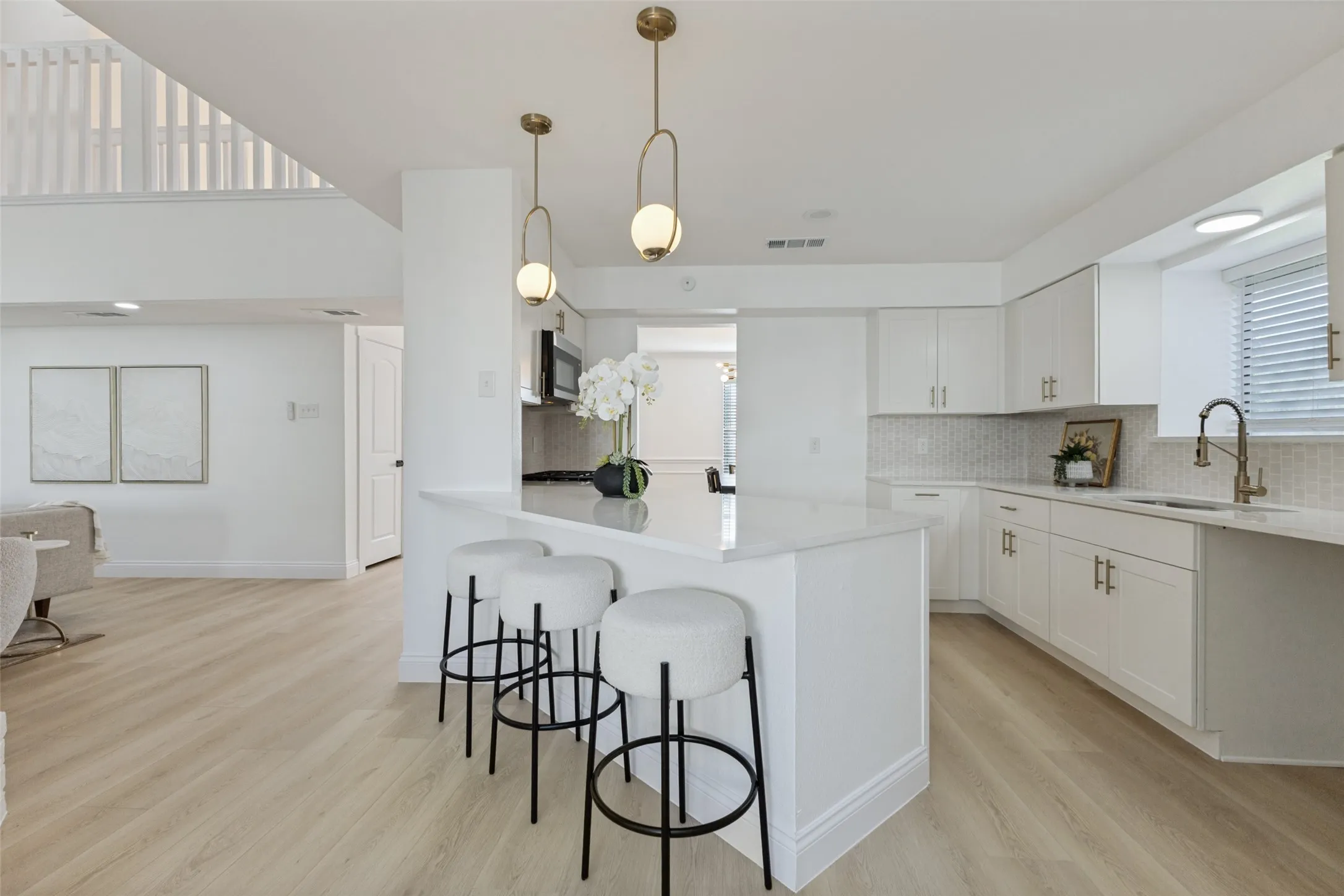Kitchen featuring white cabinetry, luxury vinyl plank flooring, a central island with countertop seating, stainless steel appliances, and pendant lighting