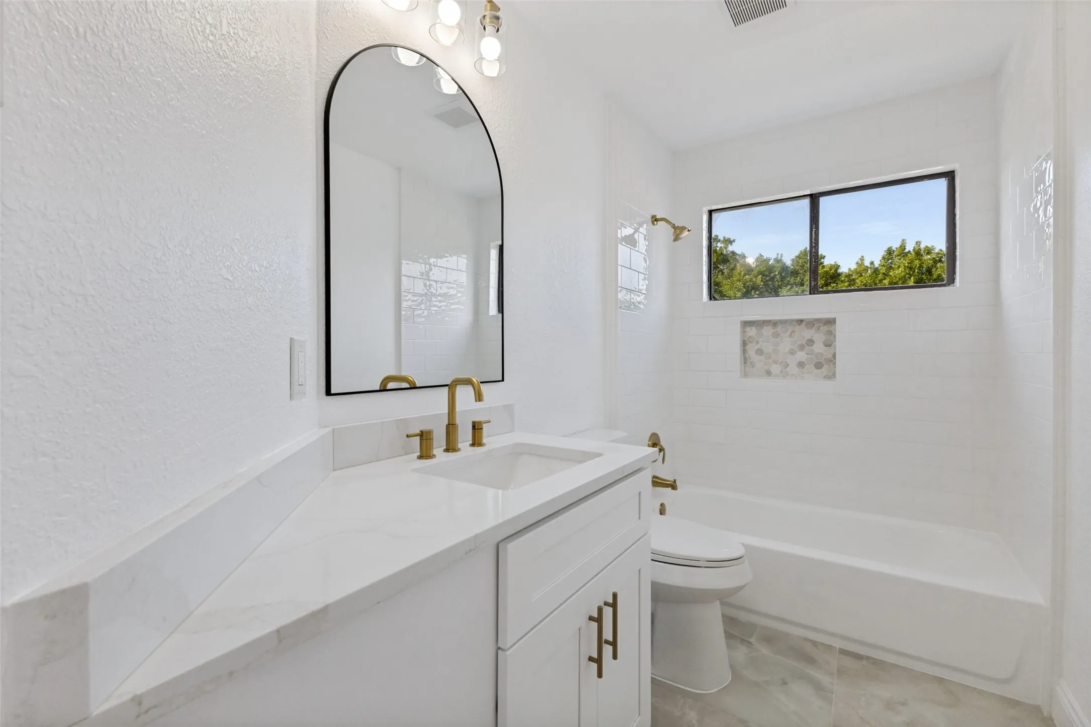 Upstairs full bath with a white vanity, quartz countertop, undermount sink, and brass-finish fixtures