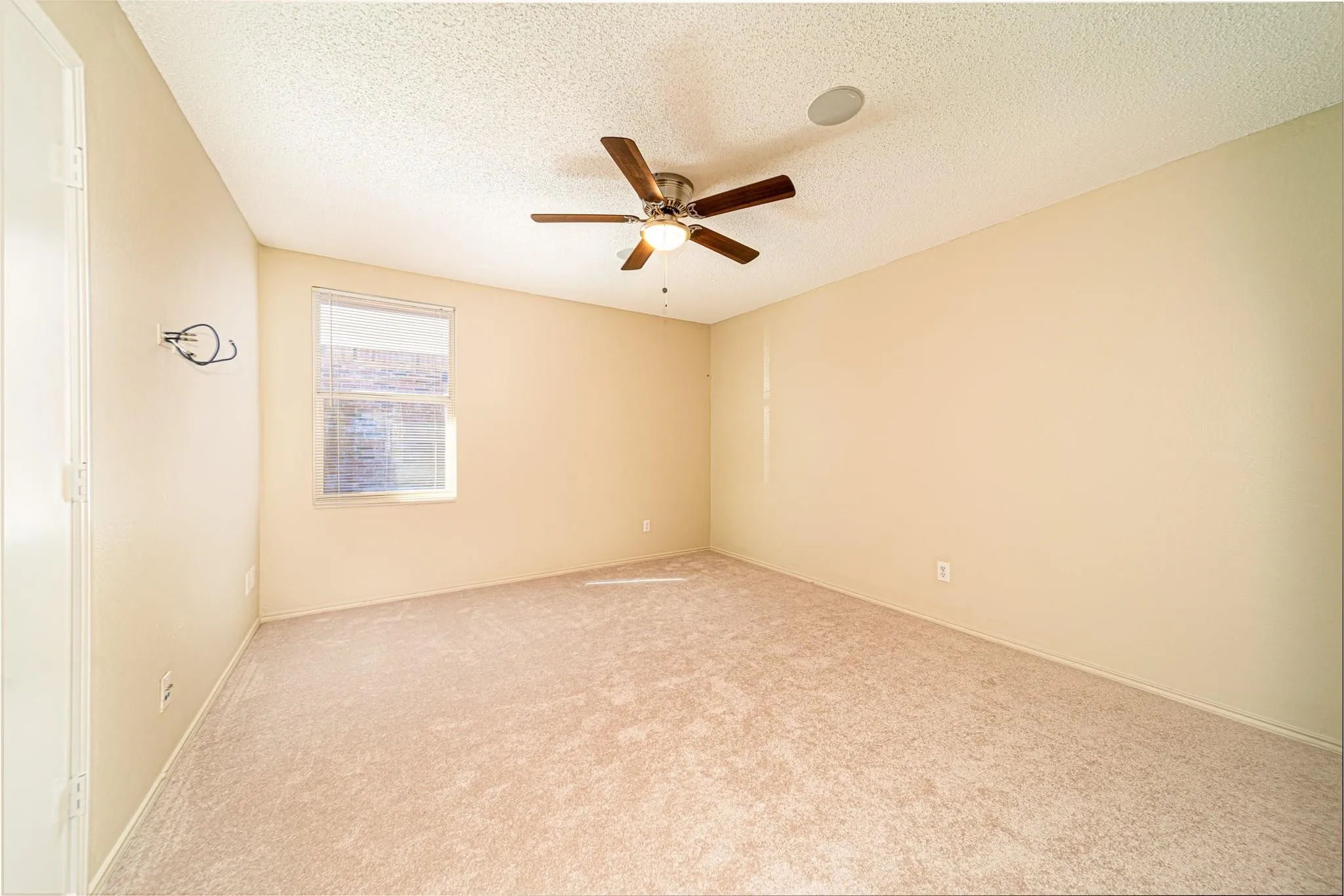 Carpeted room featuring a ceiling fan with integrated lighting, a recessed ceiling speaker, and a window with blinds