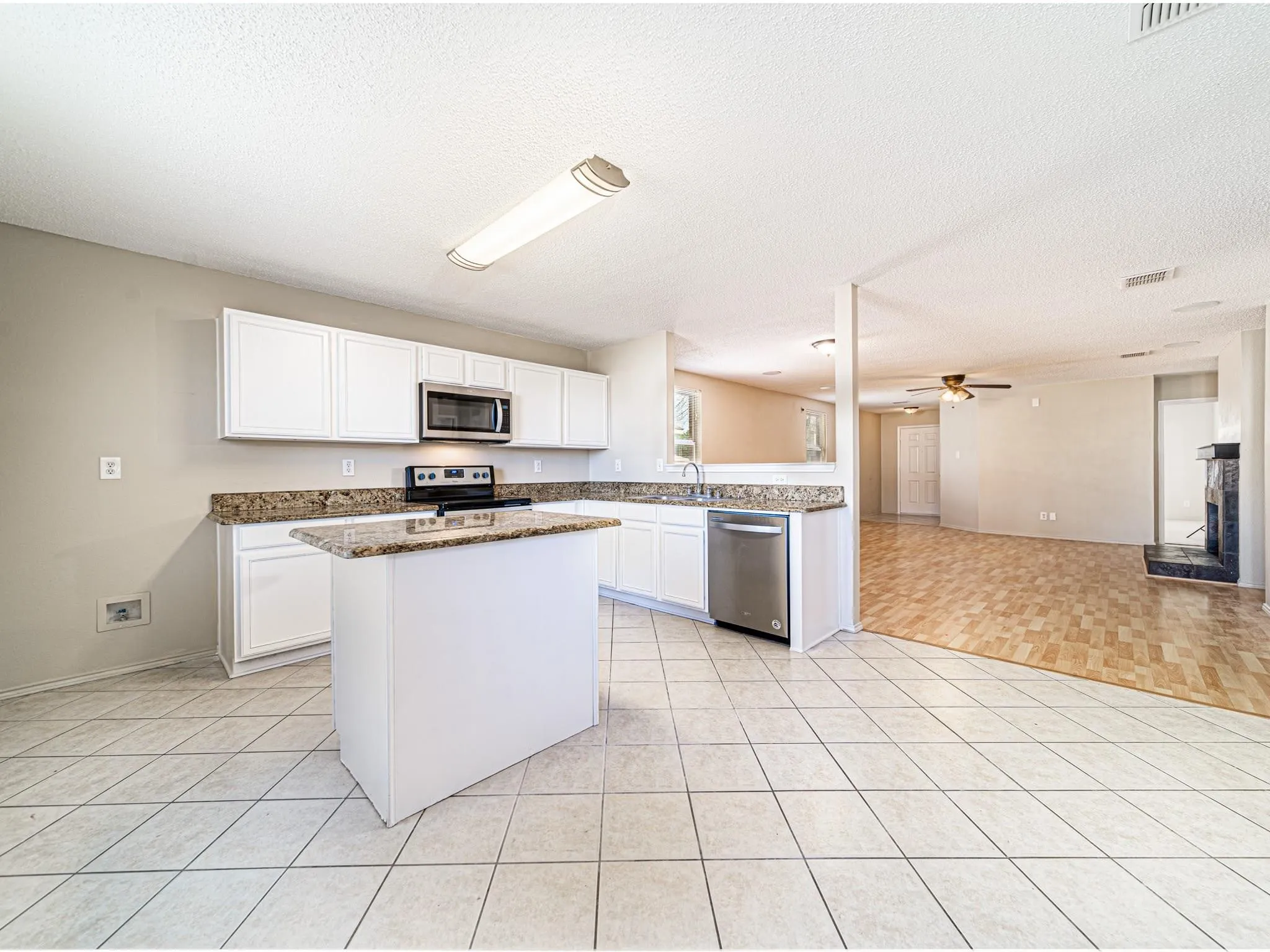 Kitchen featuring white cabinetry, granite countertops, a central island, and stainless steel appliances