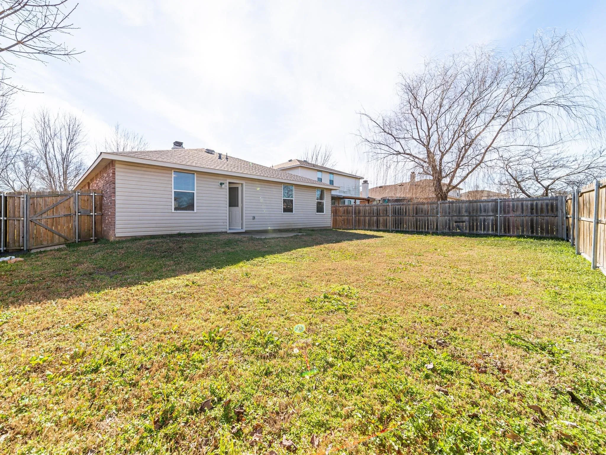 Expansive backyard featuring a partial brick exterior, horizontal siding, and a wood fence enclosure
