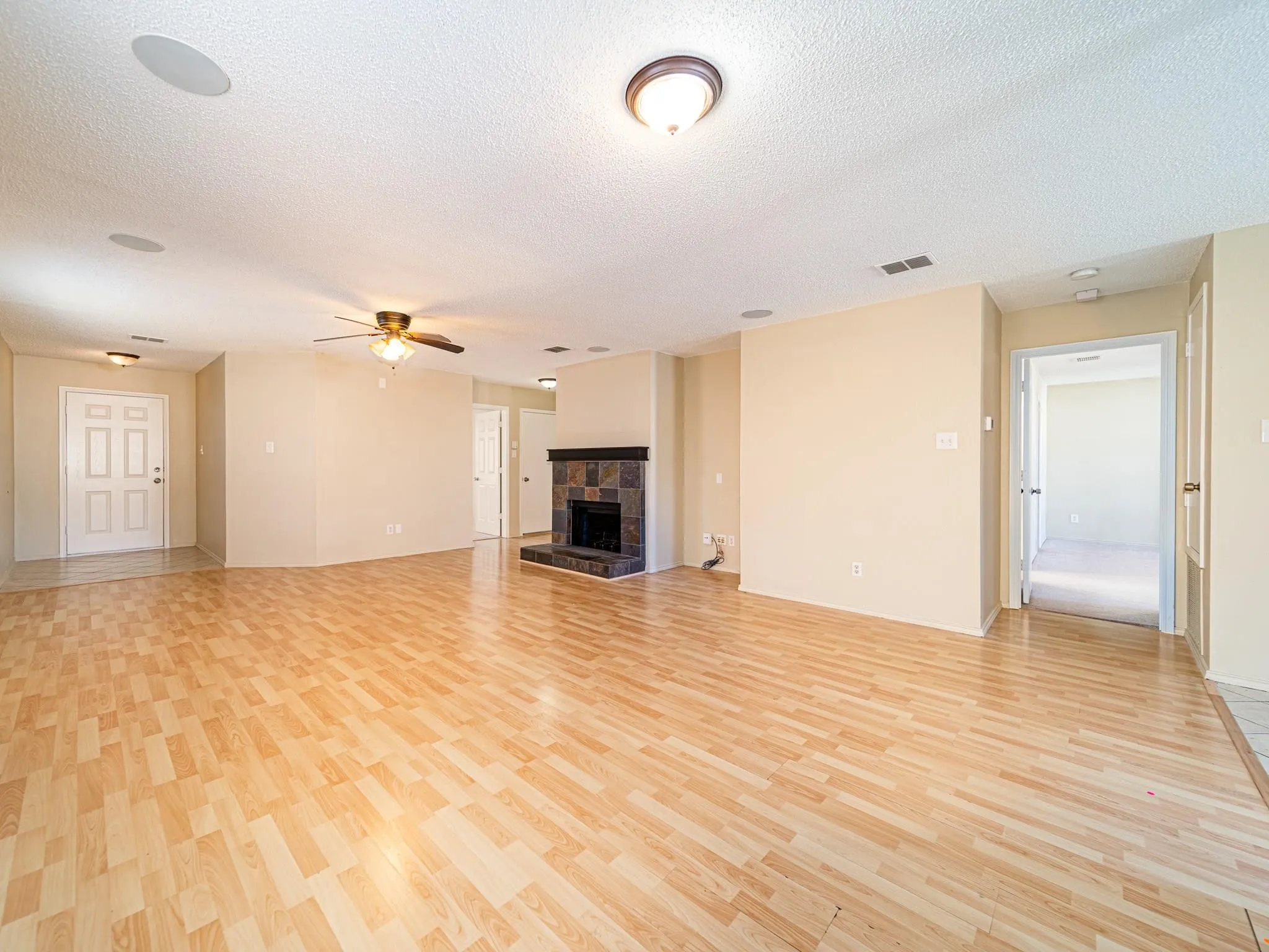 Wood-finish flooring throughout, featuring a built-in fireplace with stone tile surround, recessed lighting, and a ceiling fan
