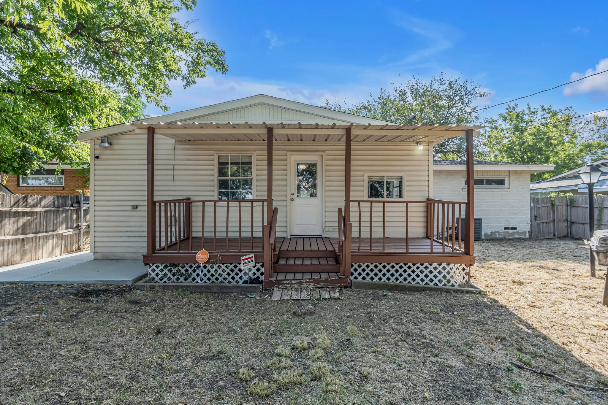 Rear exterior featuring a covered wood deck, vinyl siding, and a fenced yard