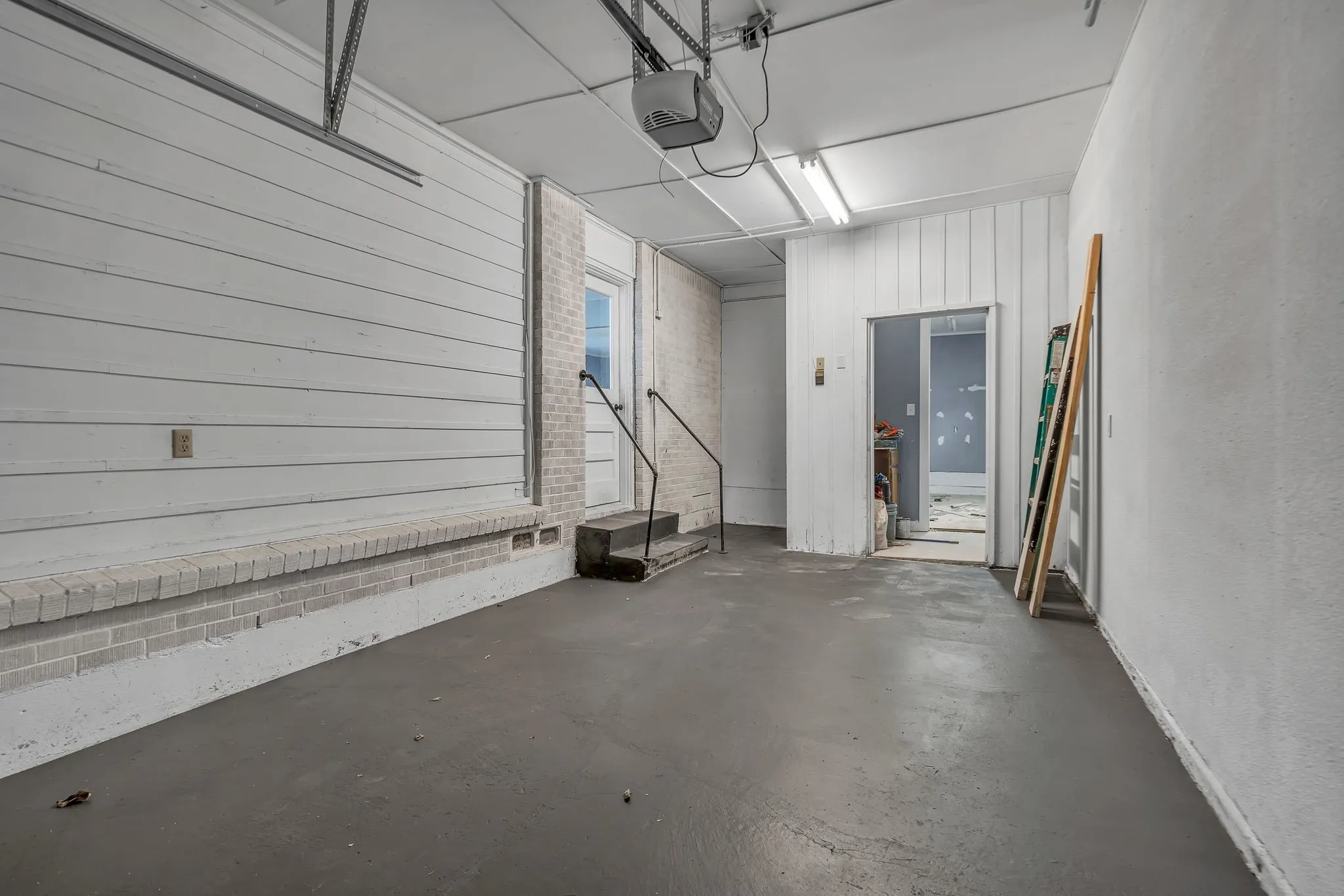 Garage with a gray finished floor, overhead lighting, and a white paneled wall