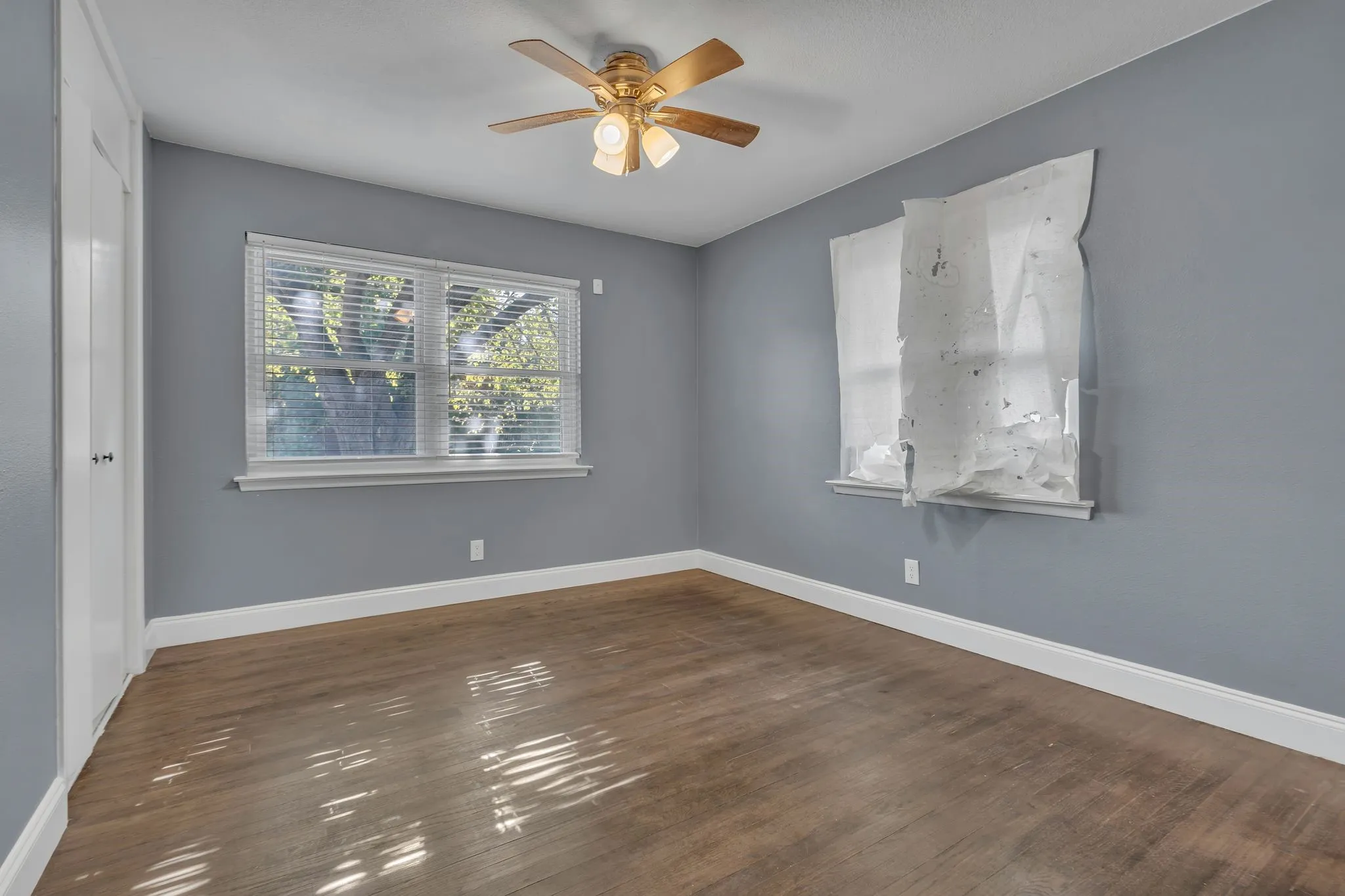 Wood-finish flooring with light gray walls, white trim, and a ceiling fan