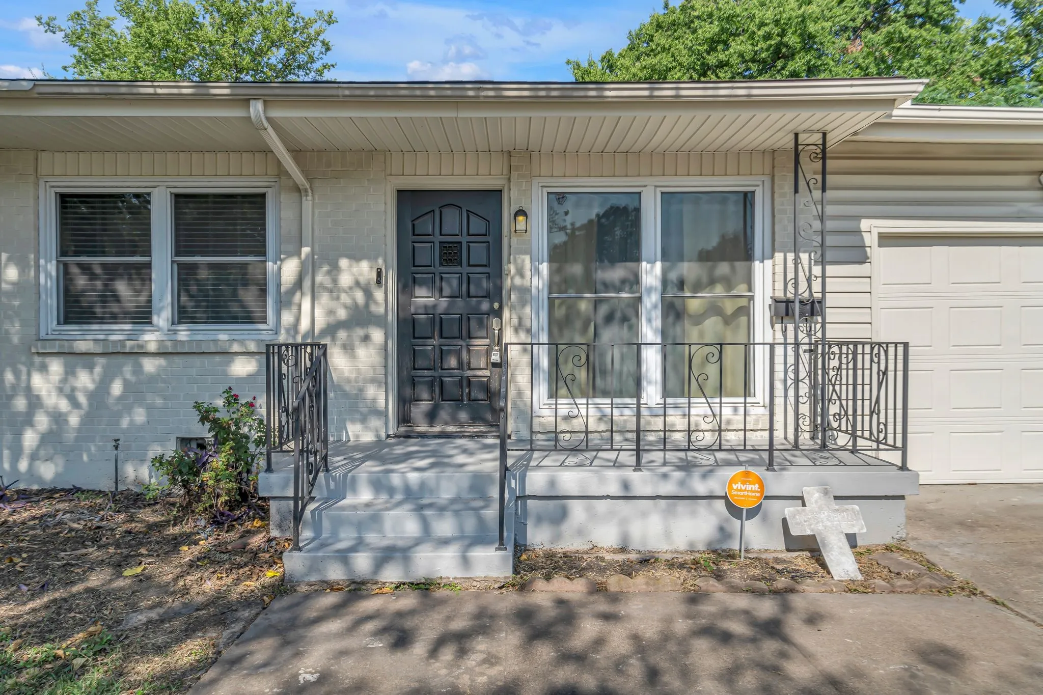 Front exterior featuring a covered entry, decorative metal railings, a paneled front door, and a single-car garage